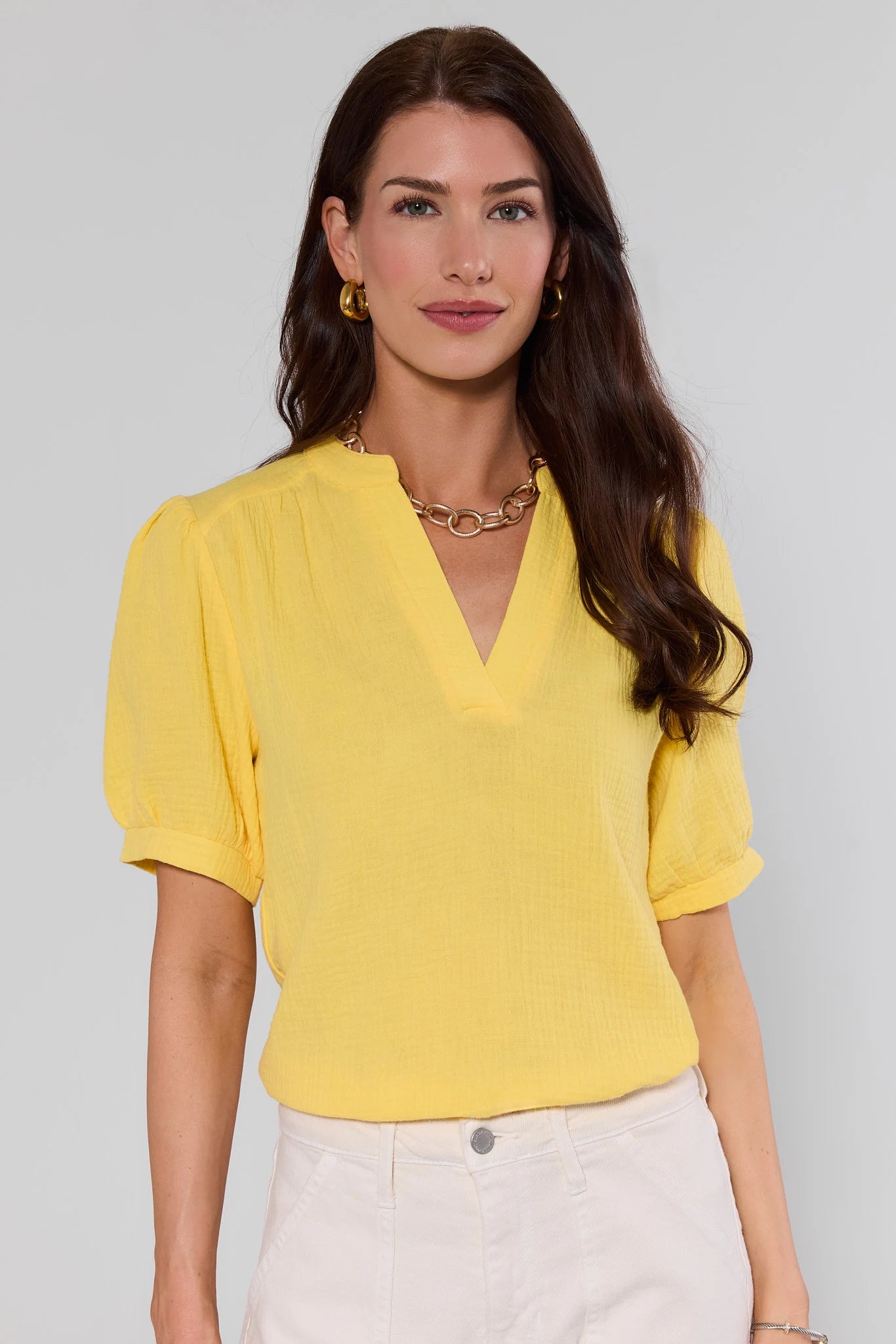 Woman wearing a yellow blouse against a gray background