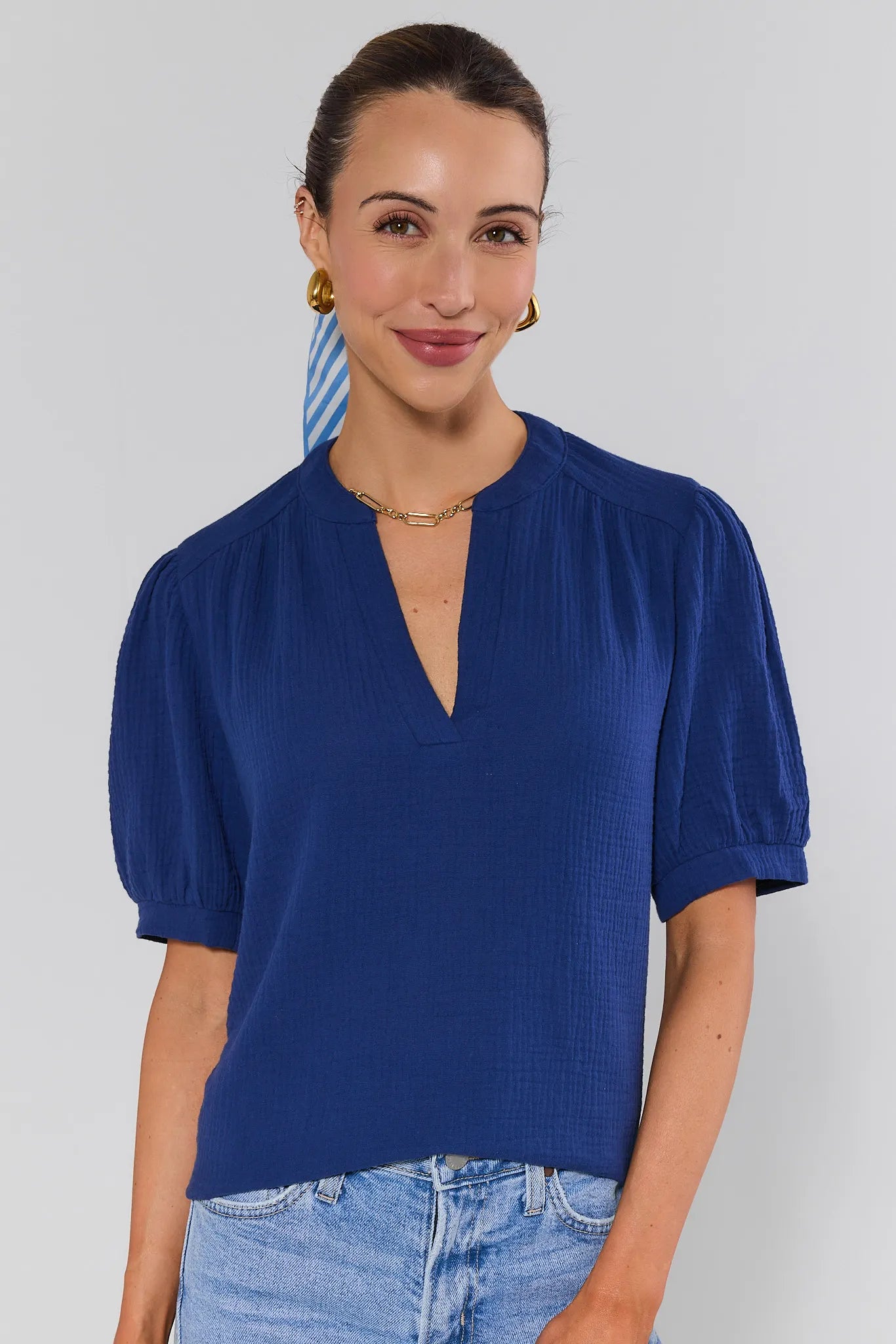 Woman wearing a blue top with puffed sleeves against a plain background