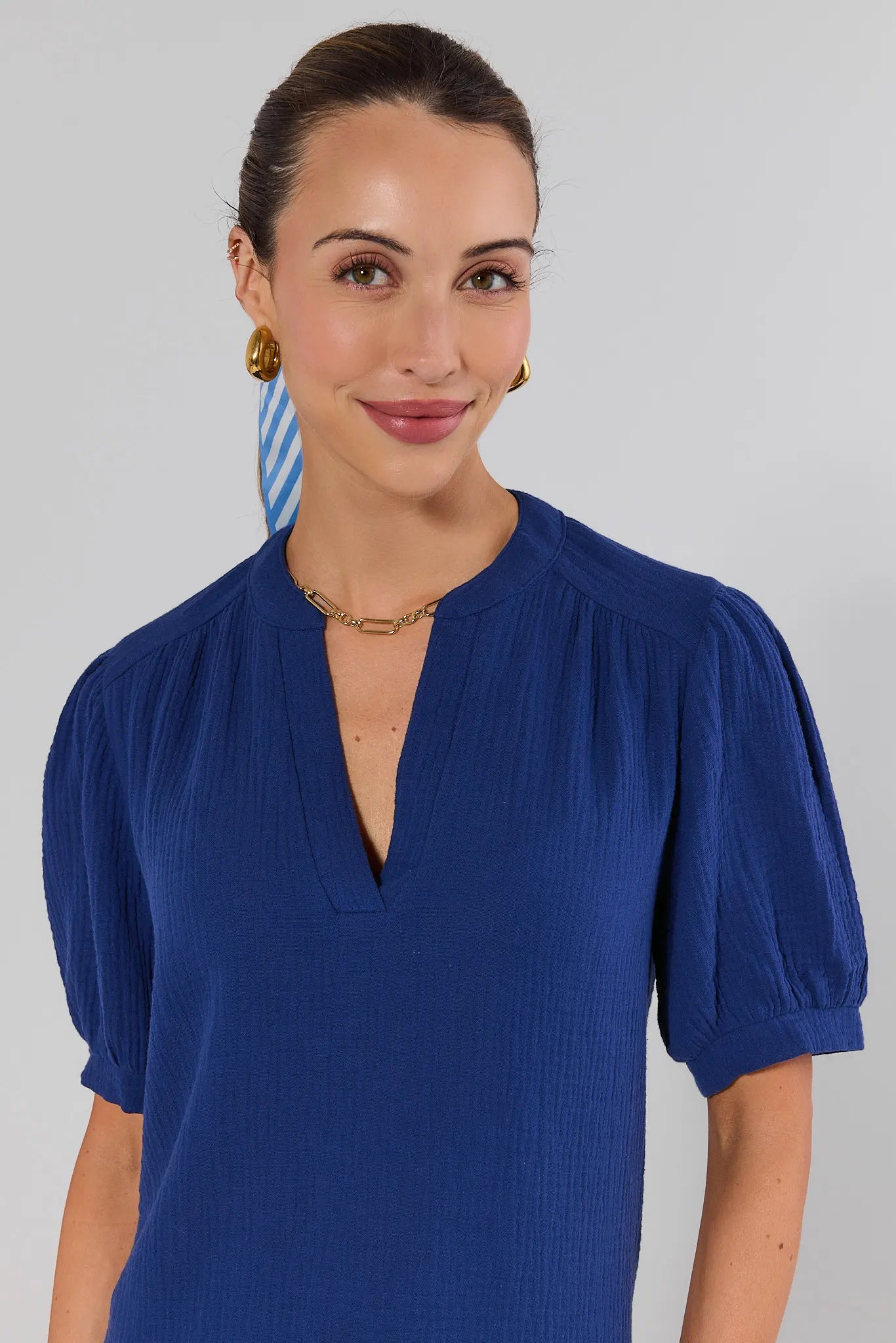 close up Woman wearing a blue dress with puffed sleeves against a gray background