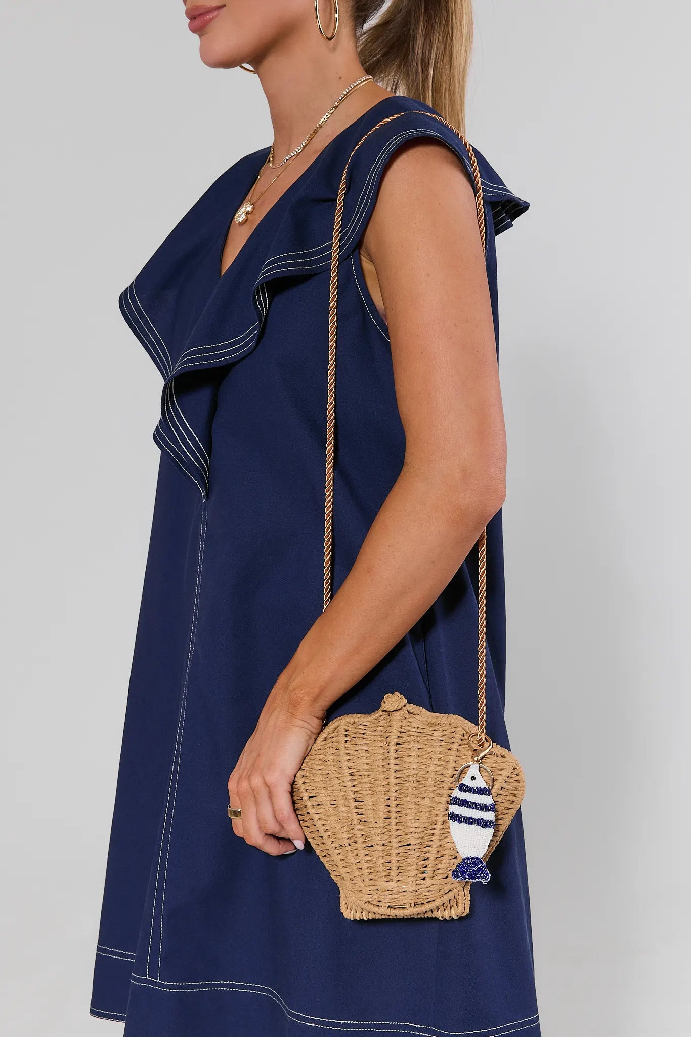 Woman holding a wicker handbag with a decorative element against a plain background