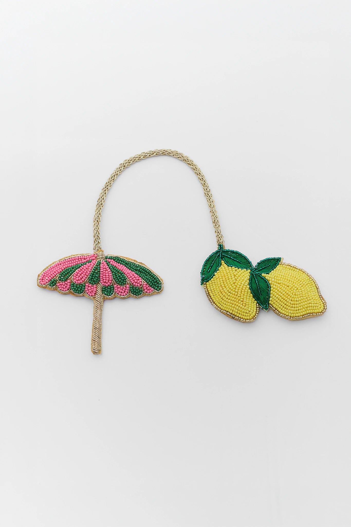 Embroidered accessories including a pink umbrella and lemon design on a white background