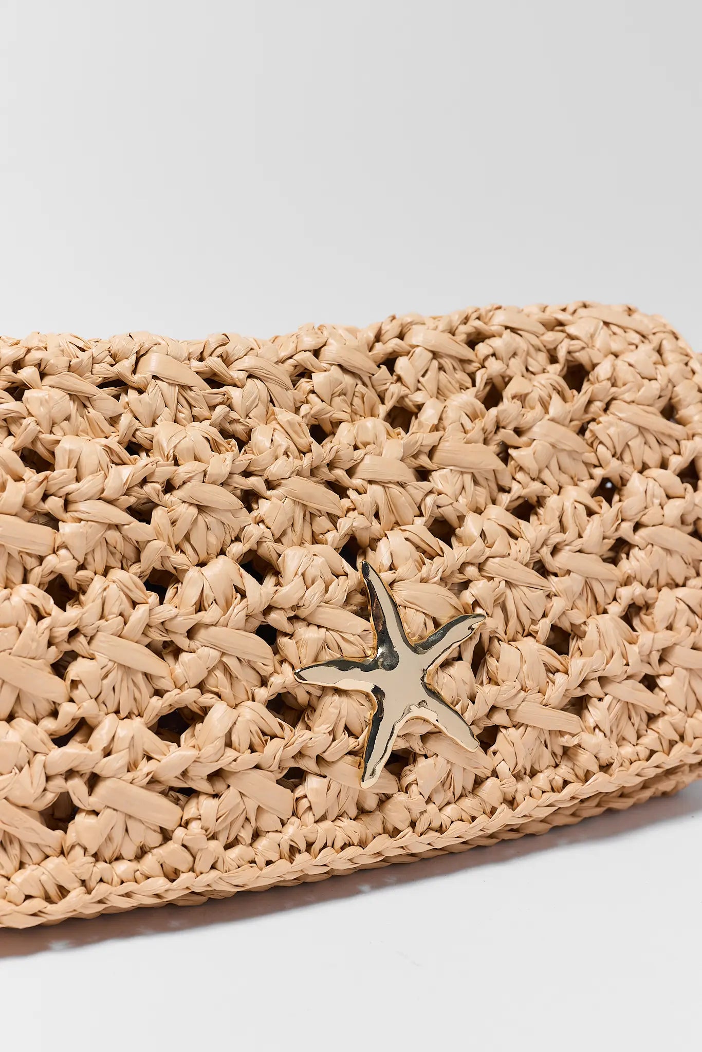 close up Woven clutch bag with starfish charm on a light gray background