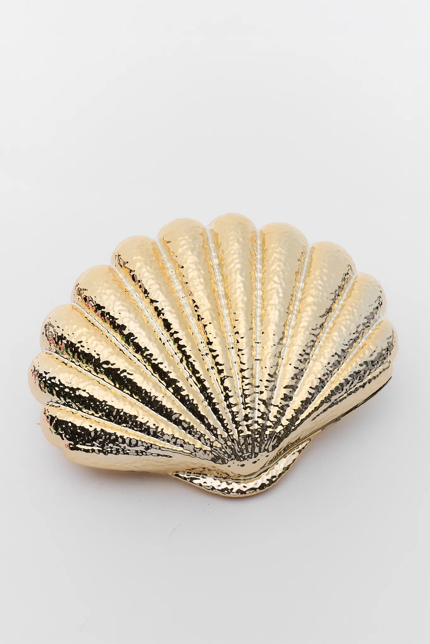 Gold shell-shaped clutch on a white background