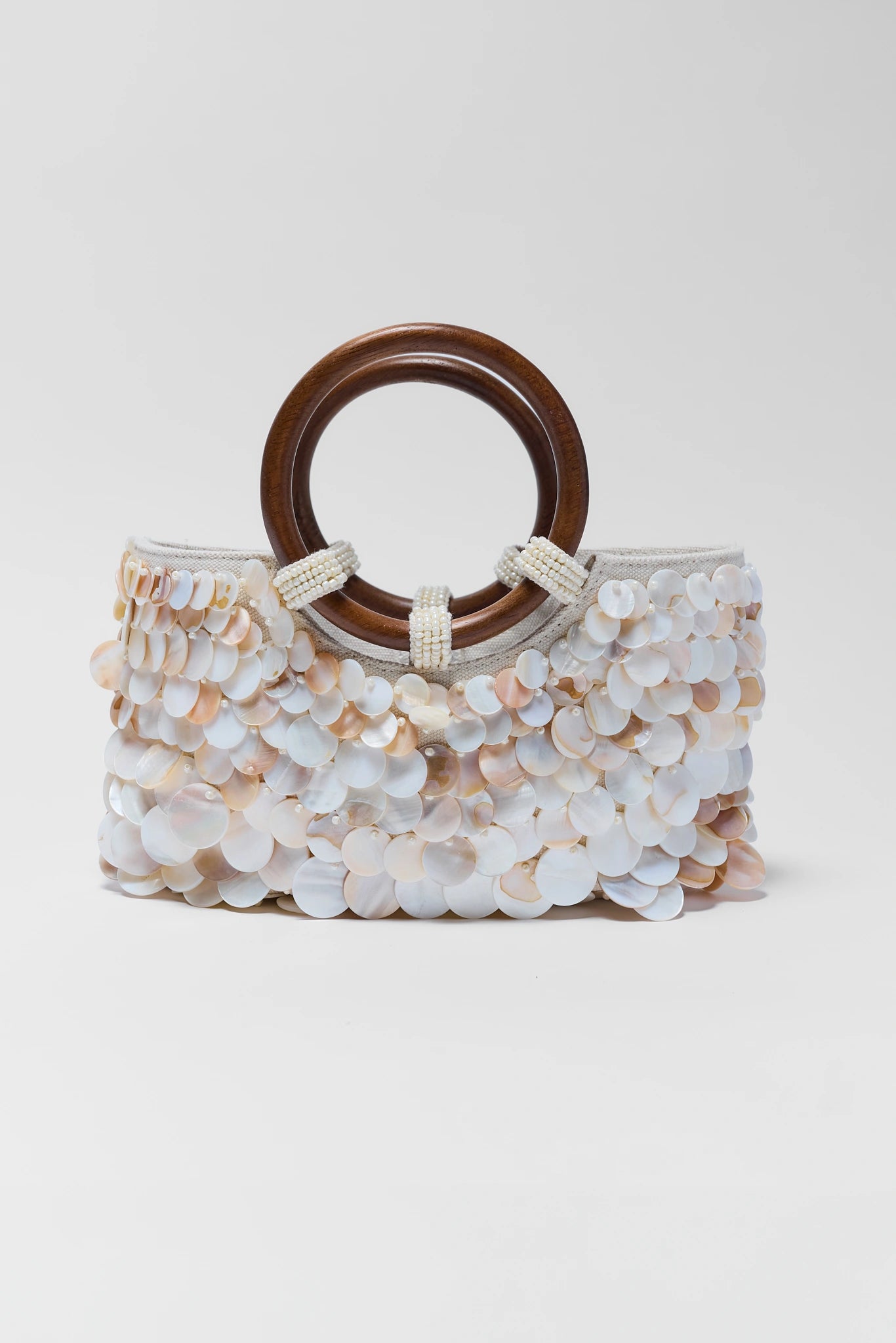 Handbag with wooden handle and shell-like embellishments on a white background one