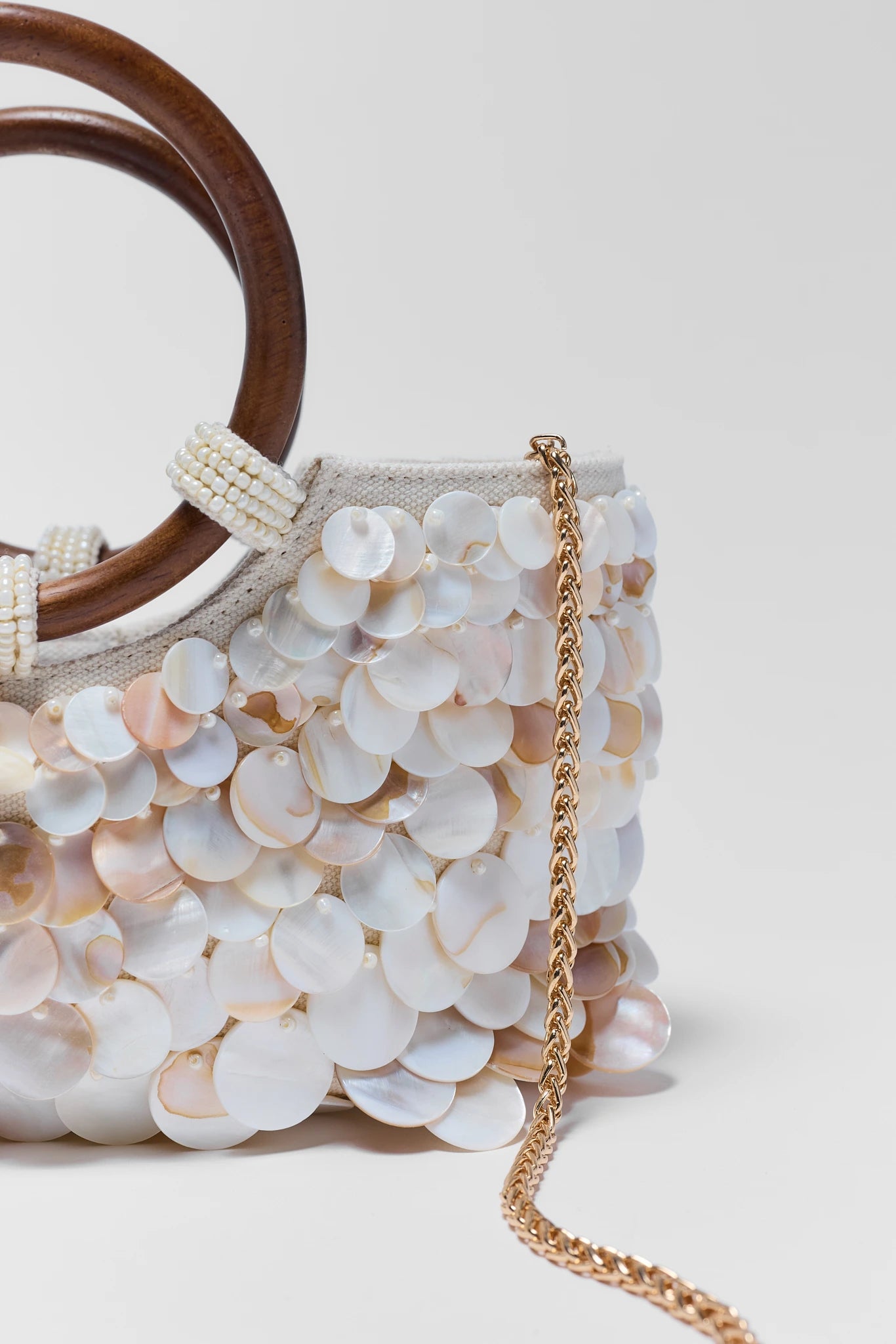 close up Handbag with shell-like design and wooden handle on a light background