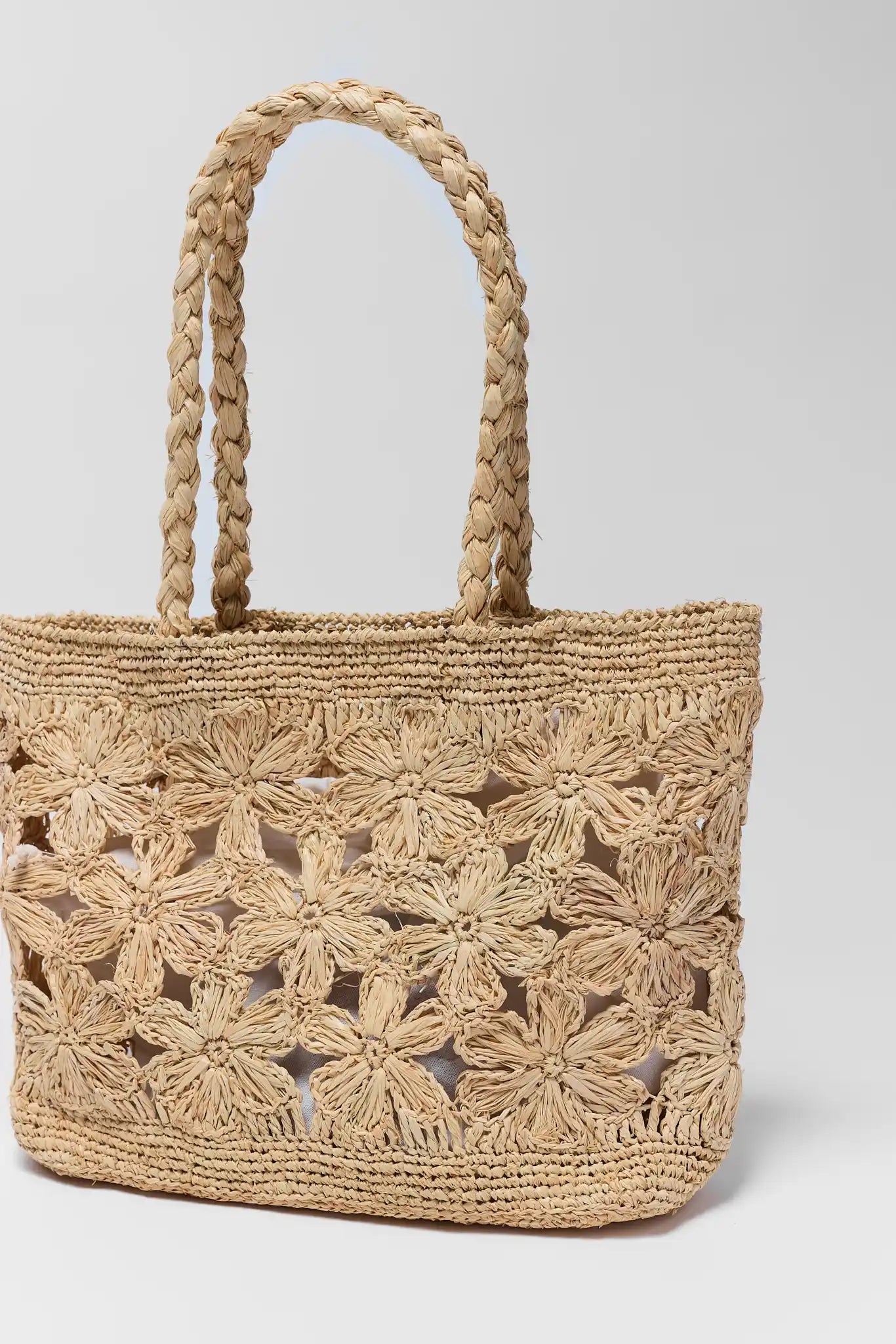 Woven handbag with floral patterns on a light gray background close up