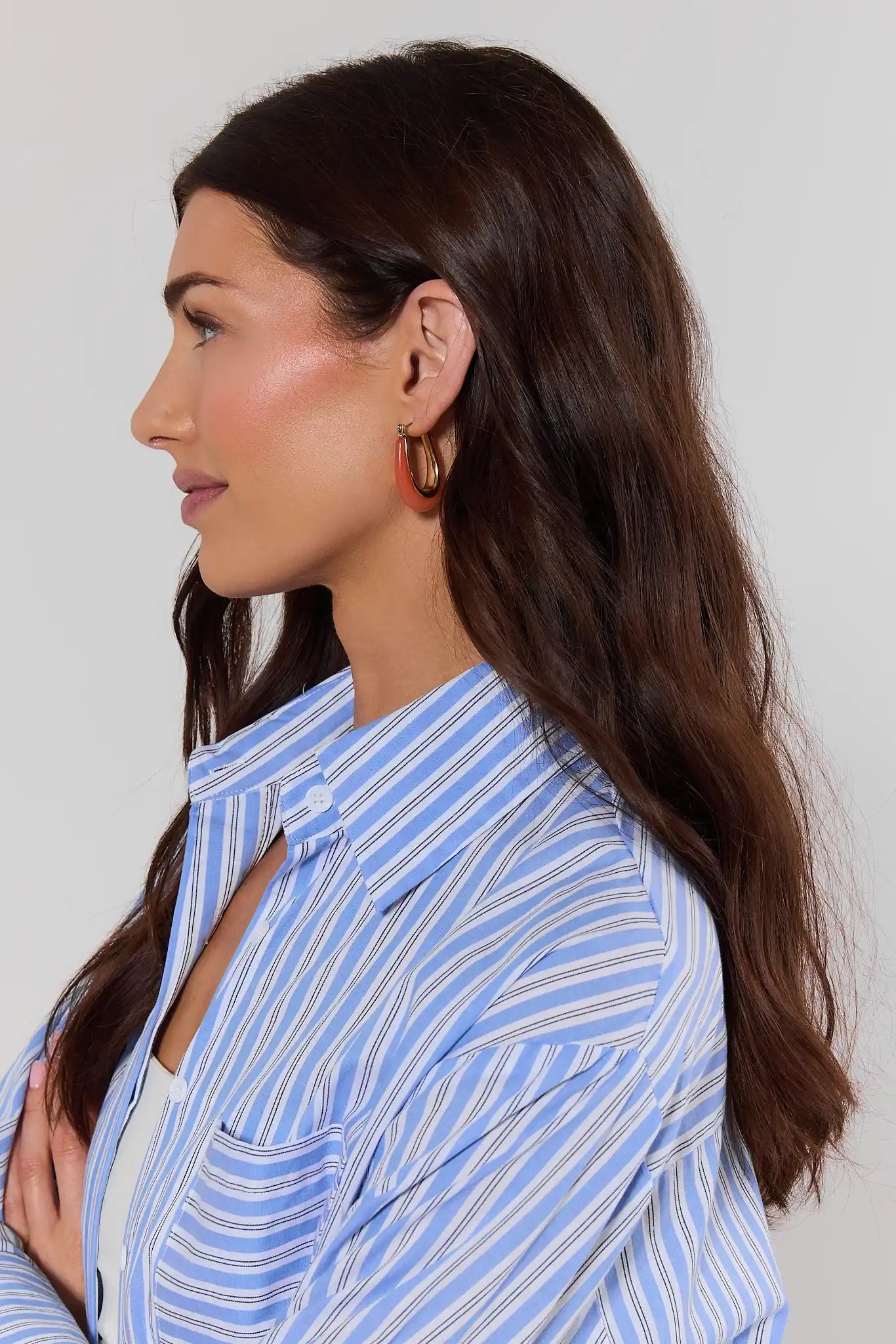 Woman wearing a blue striped shirt with a plain background
