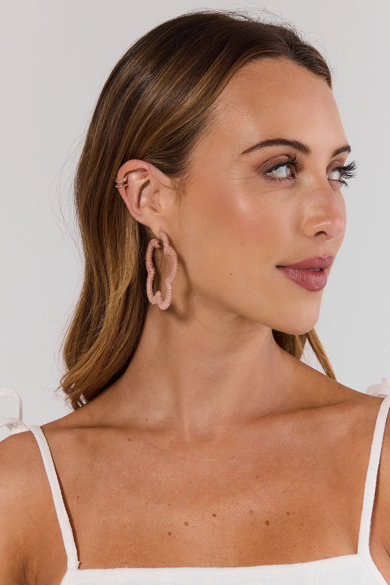 Woman wearing hoop earrings with a plain background