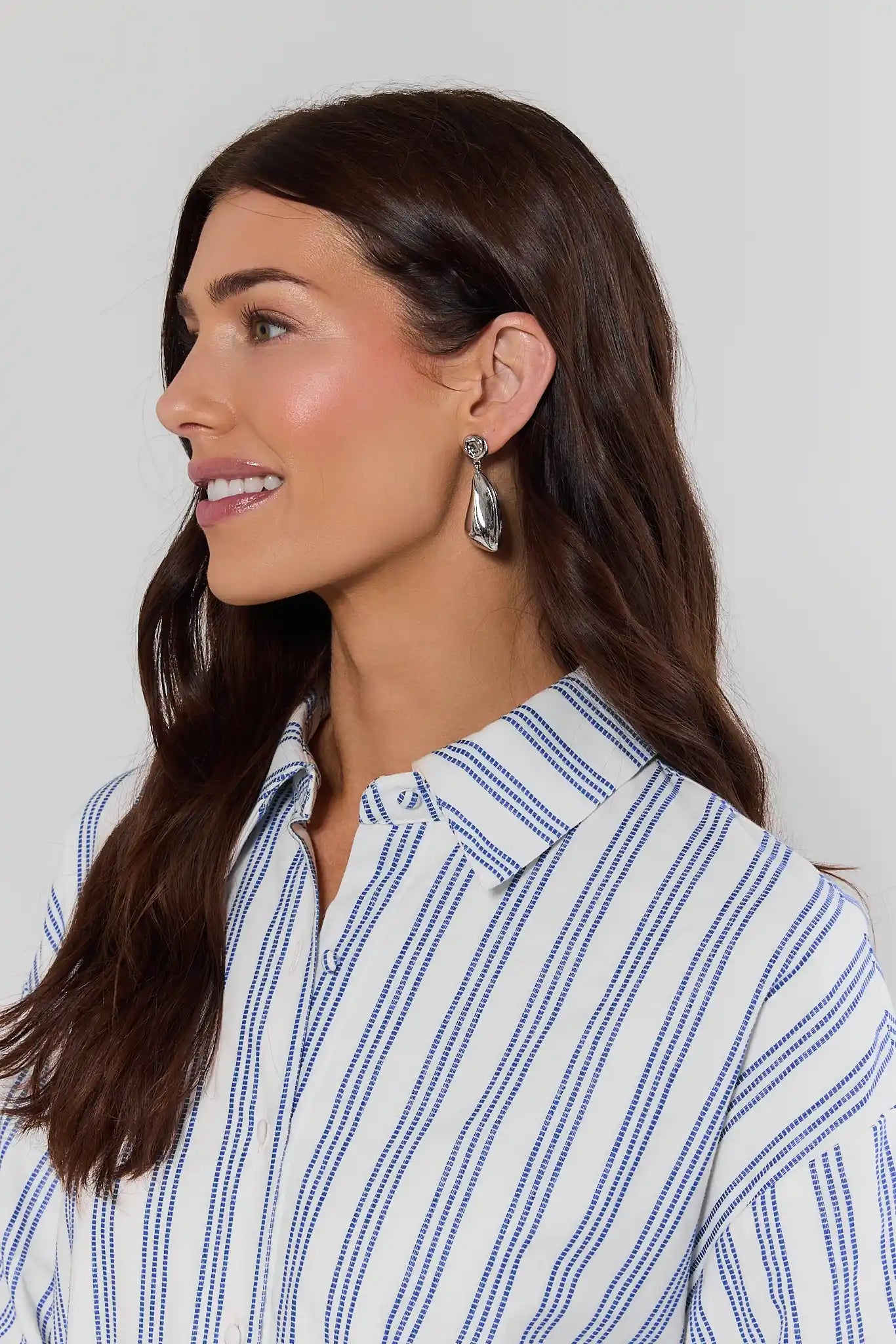 Woman wearing a blue and white striped shirt with a neutral background
