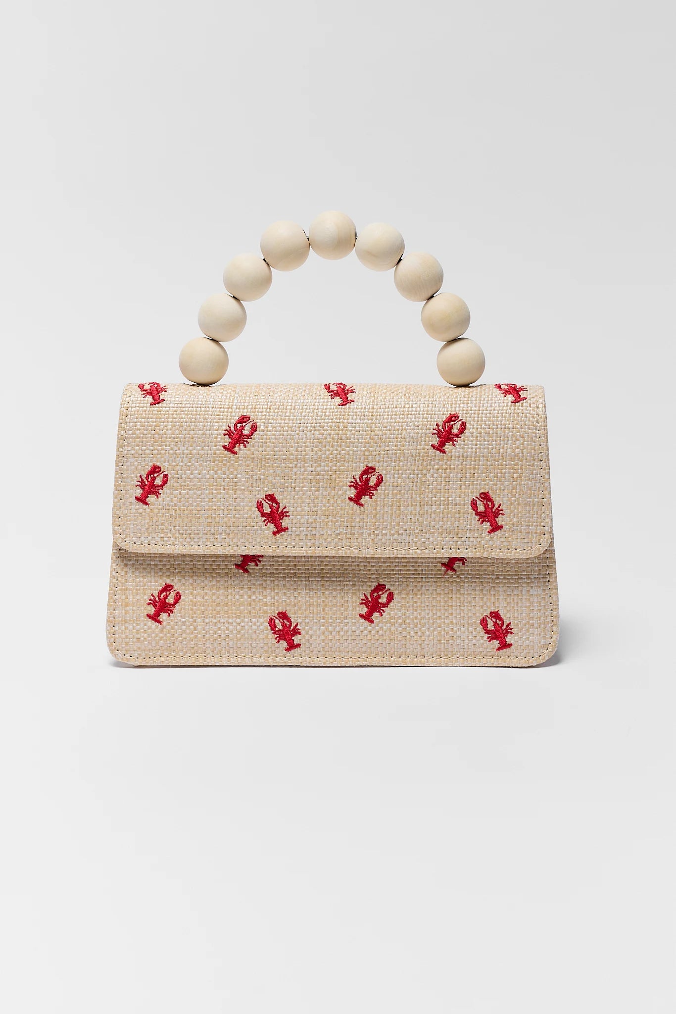 Beige handbag with red lobster pattern and wooden bead handle on a light gray background