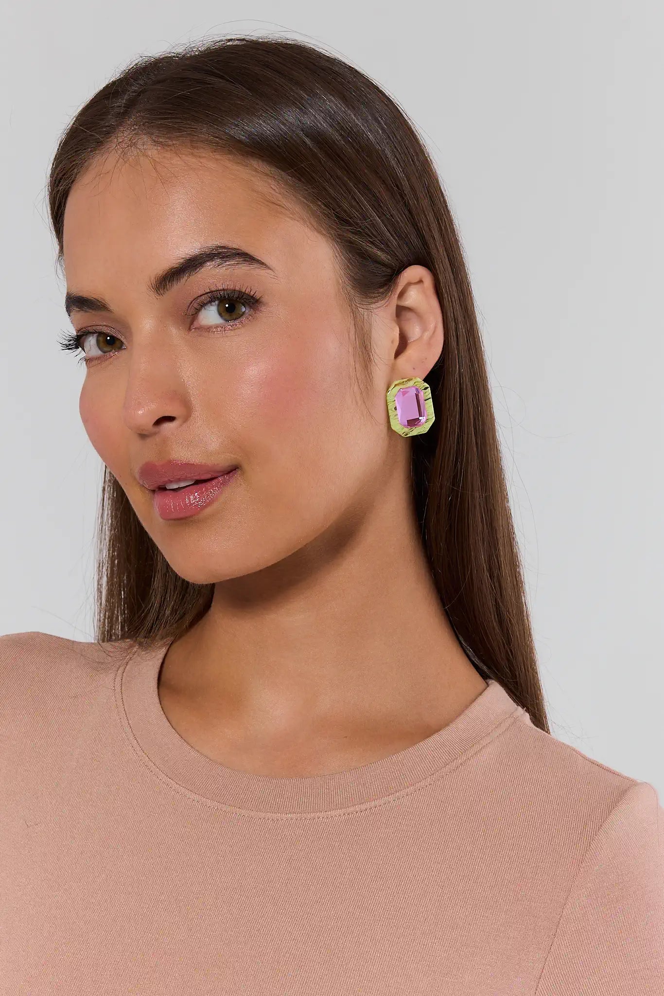 Woman wearing pink earrings against a neutral background