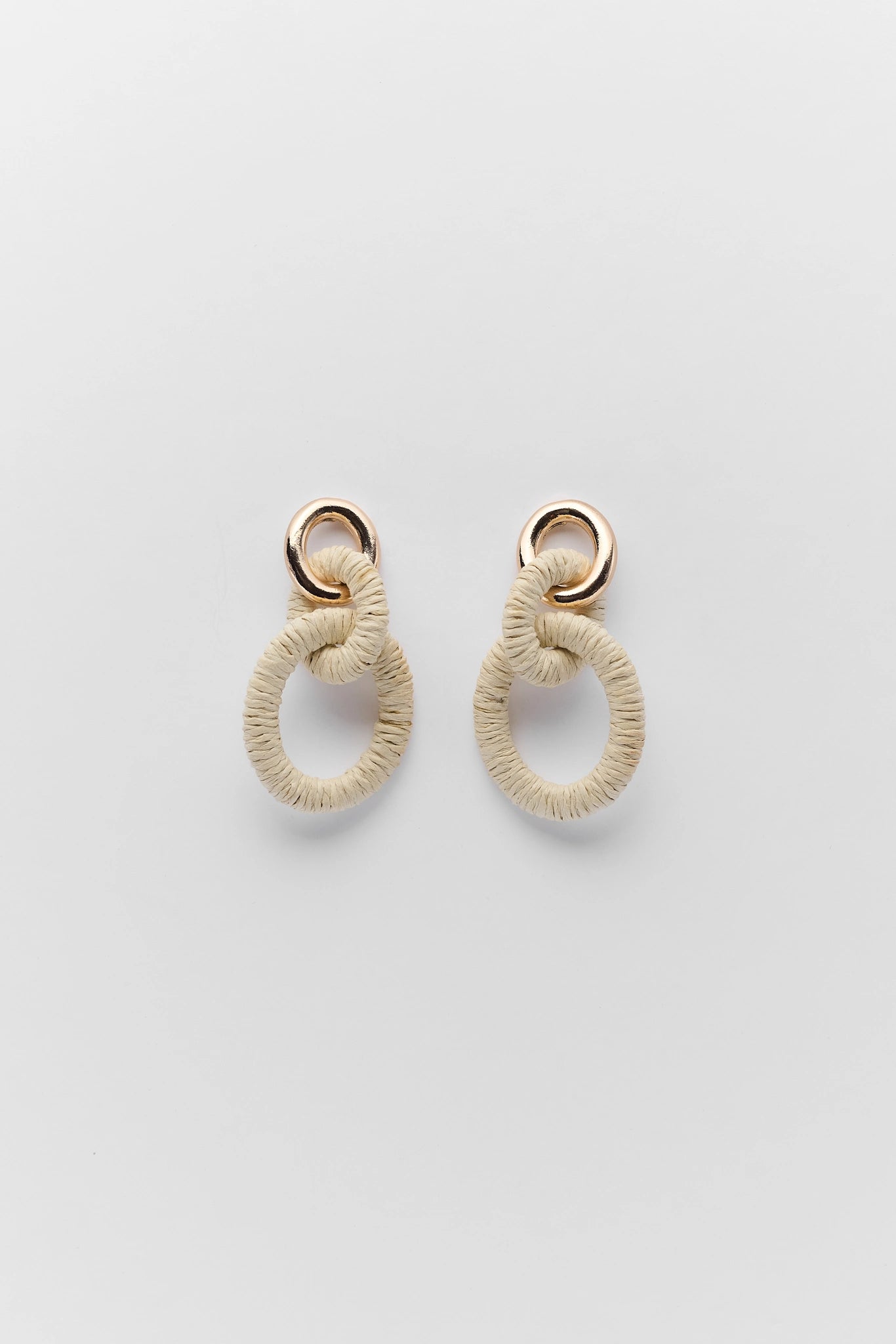 Pair of beige hoop earrings on a light gray background