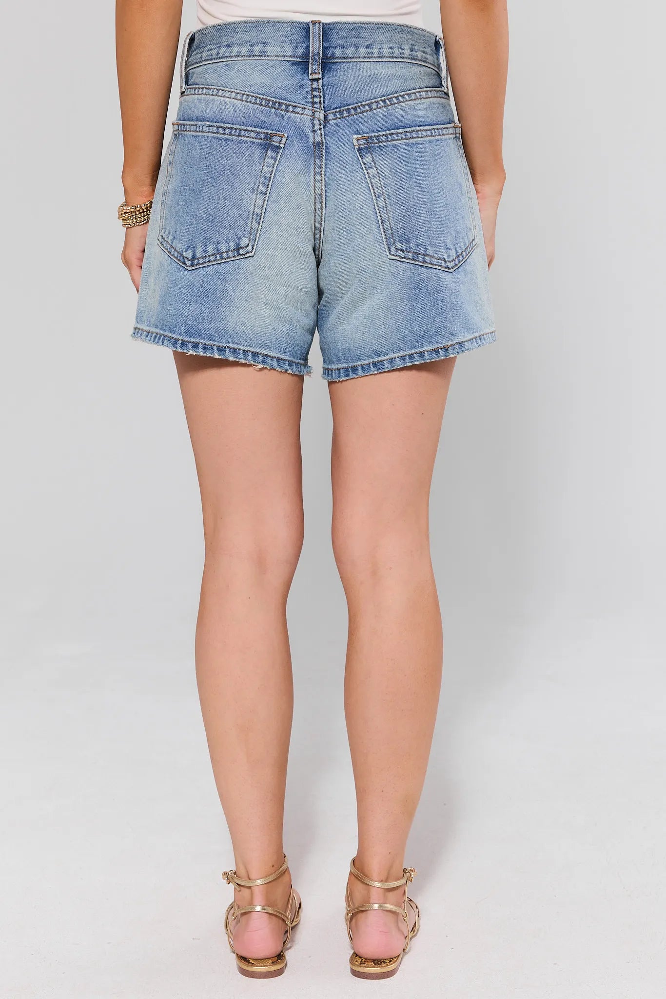 standing Denim shorts worn by a person on a plain background