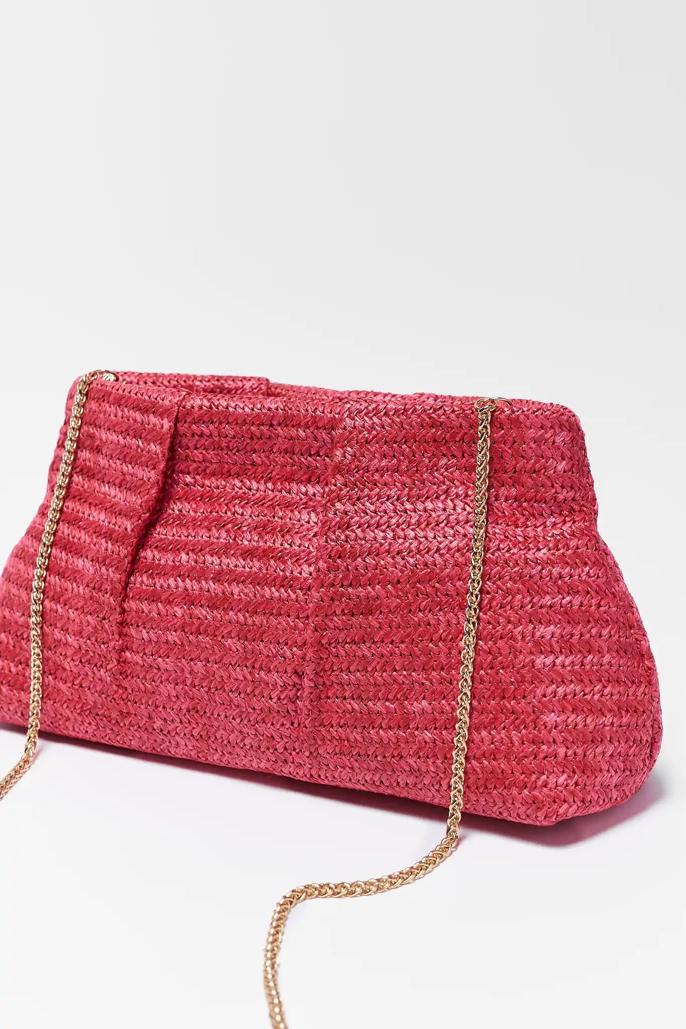 Pink woven handbag with a chain strap on a white background