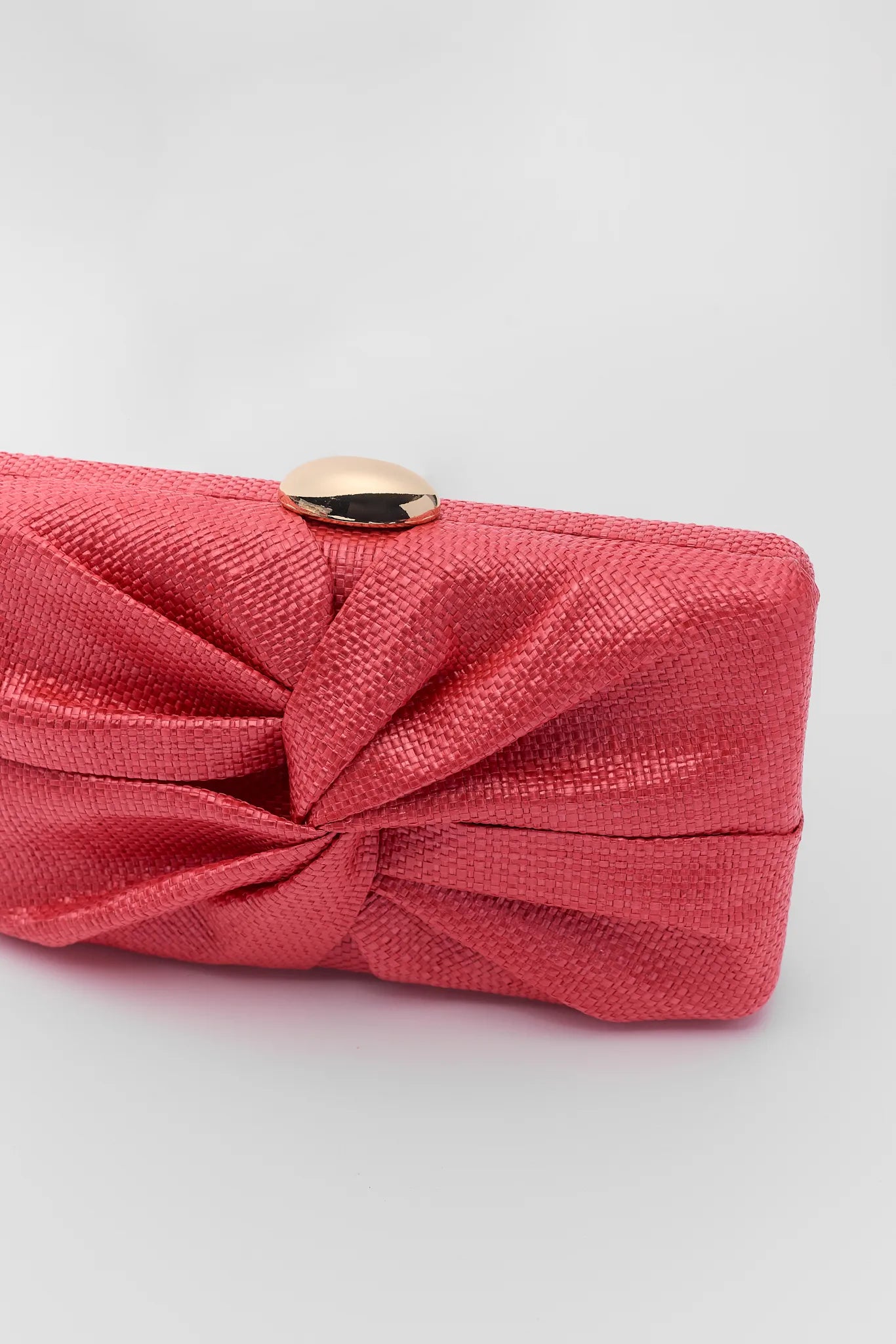 close up Red clutch bag with a knot design on a light gray background