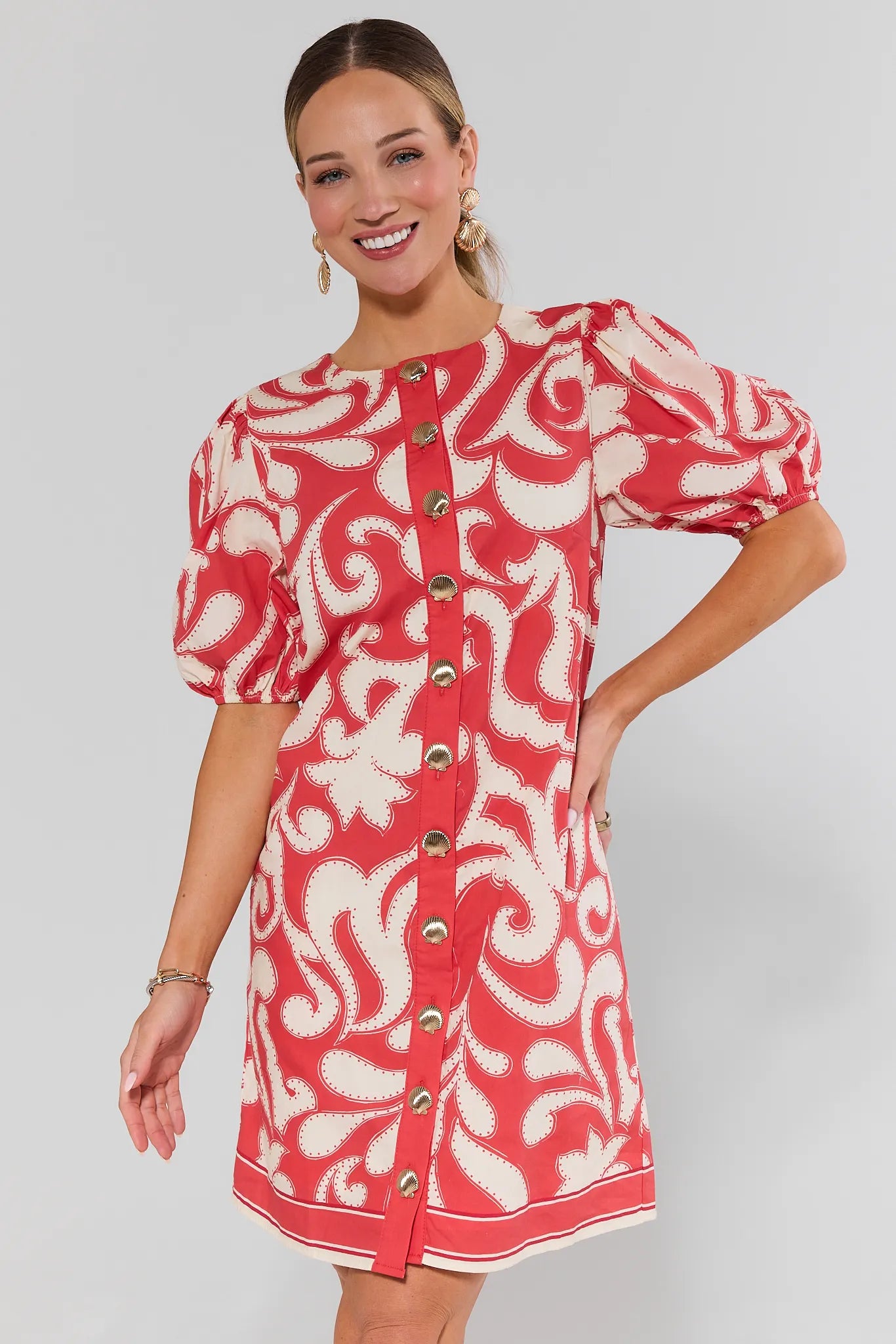 Woman wearing a red and white patterned dress with puff sleeves on a gray background
