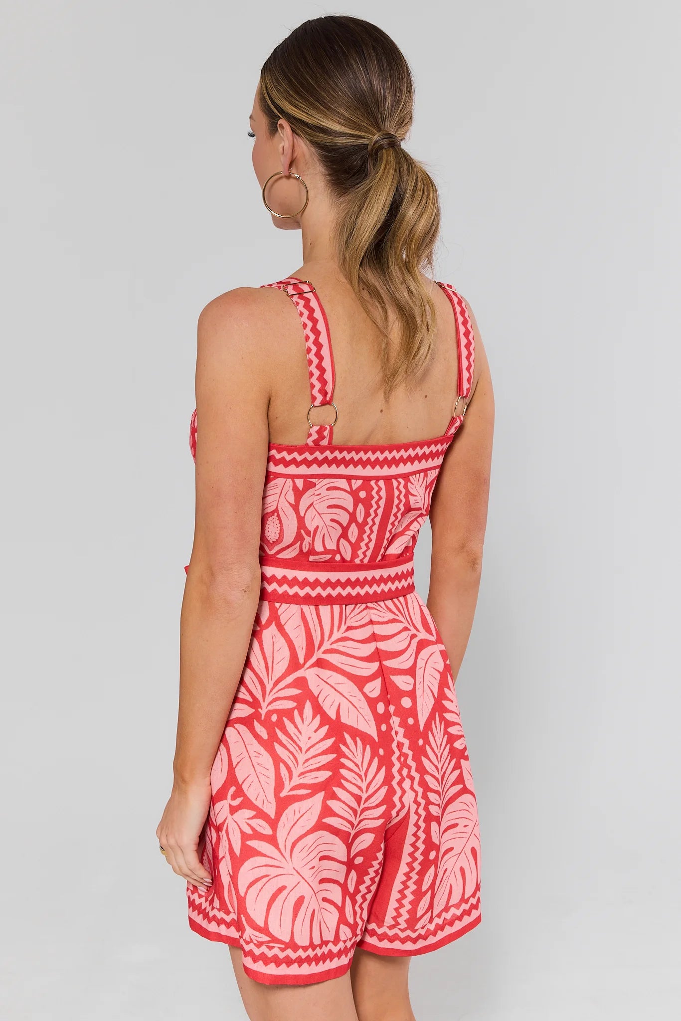 Woman standing wearing a red and white patterned dress on a plain background