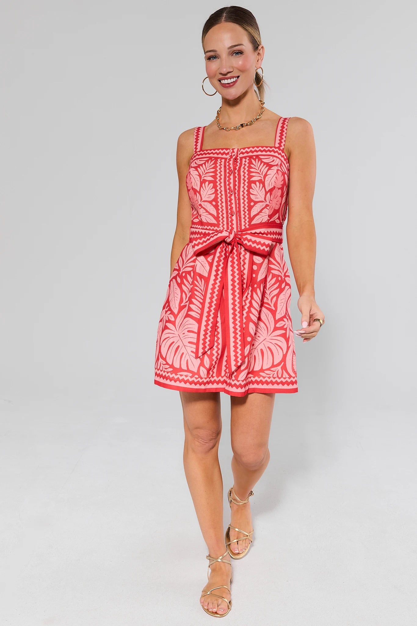 Woman wearing a red and white patterned dress and sandals on a gray background