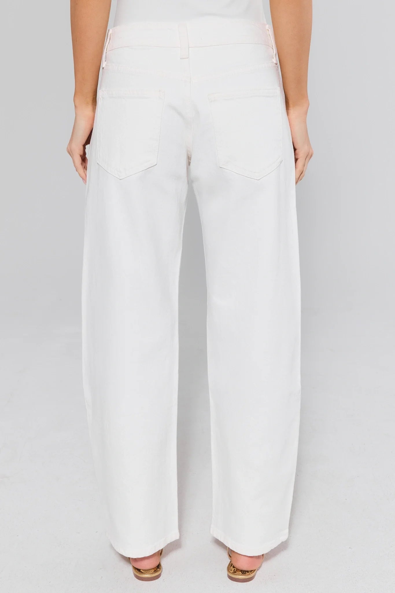 White lexi jeans worn by a person on a plain background
