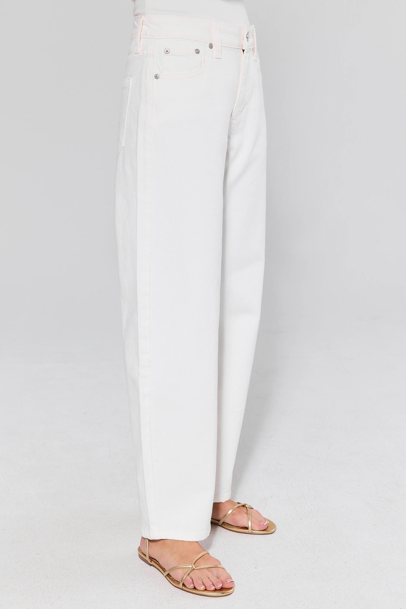 White jeans and gold sandals on a white background