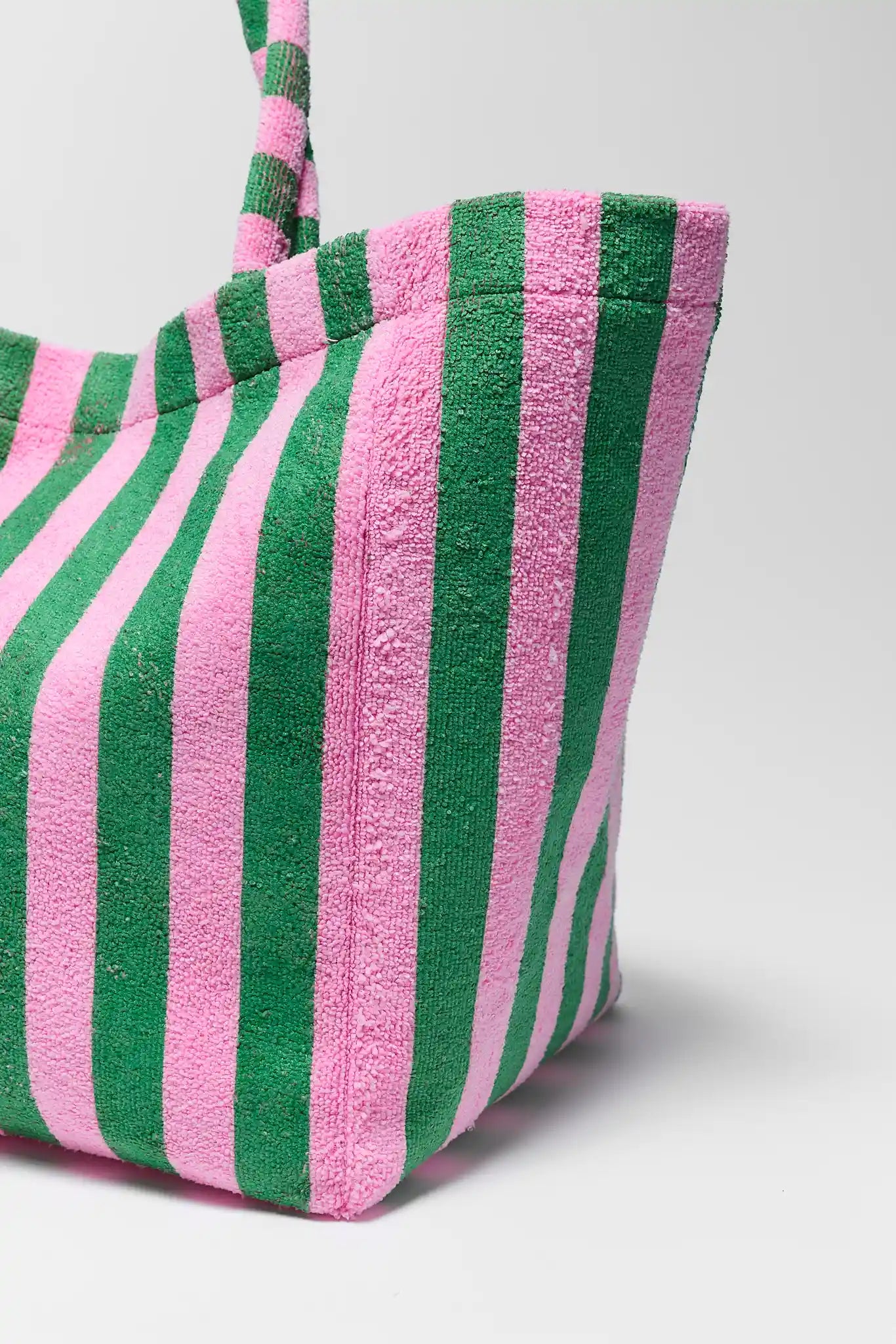 Close-up of a striped bag with pink and green horizontal stripes on a light gray background
