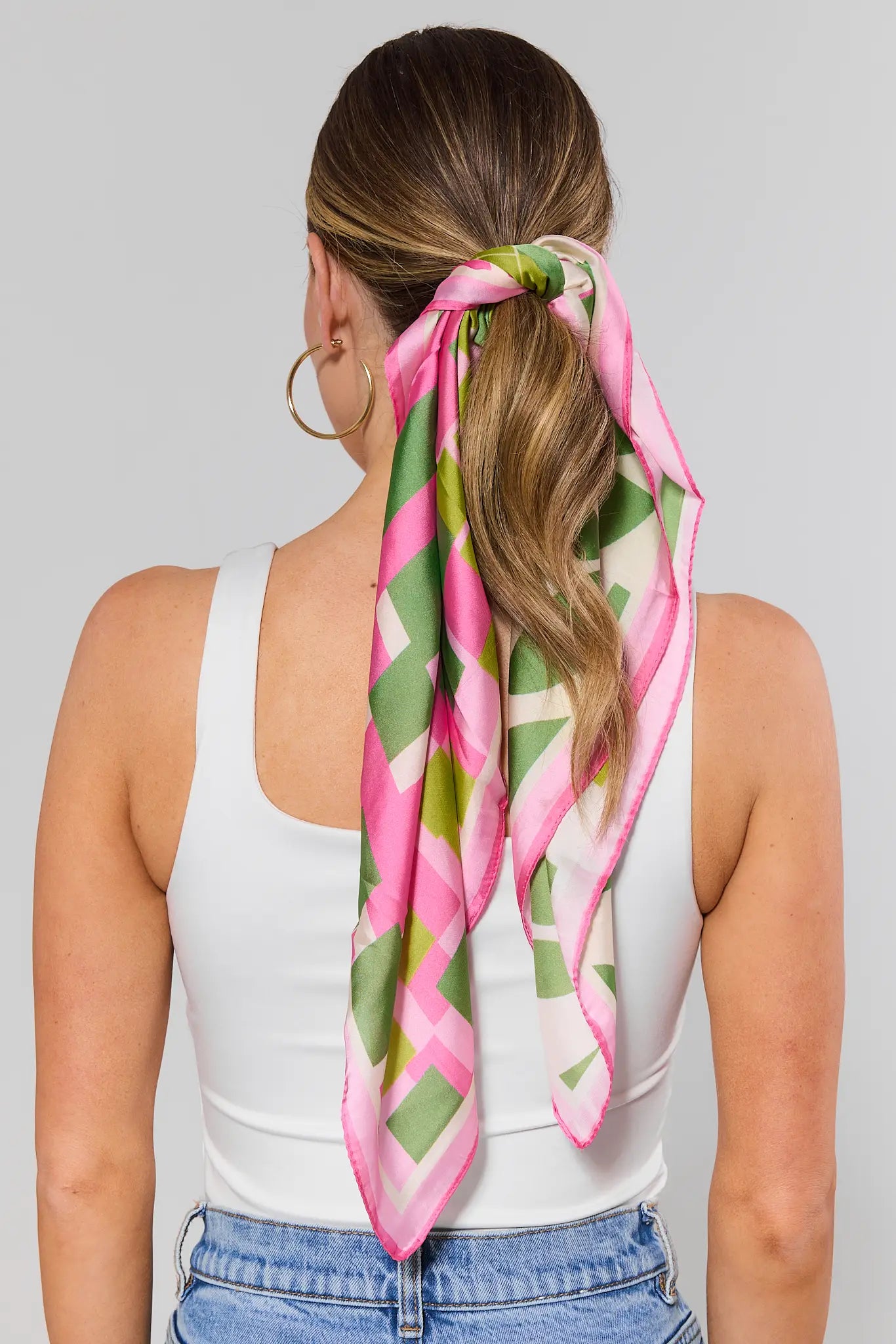 Woman wearing a colorful scarf tied around her hair against a gray background