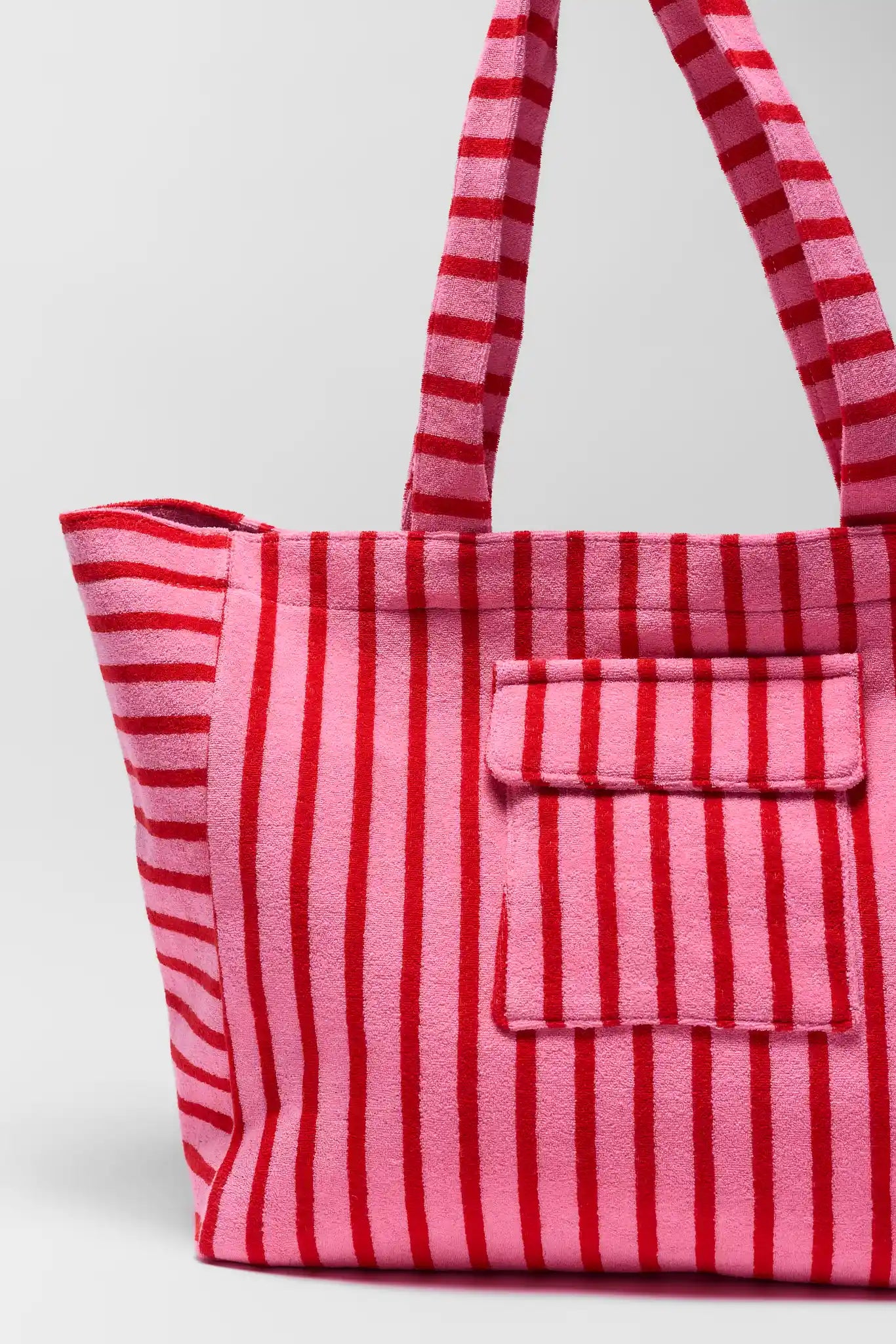 close up Red and pink striped tote bag with a pocket on a white background