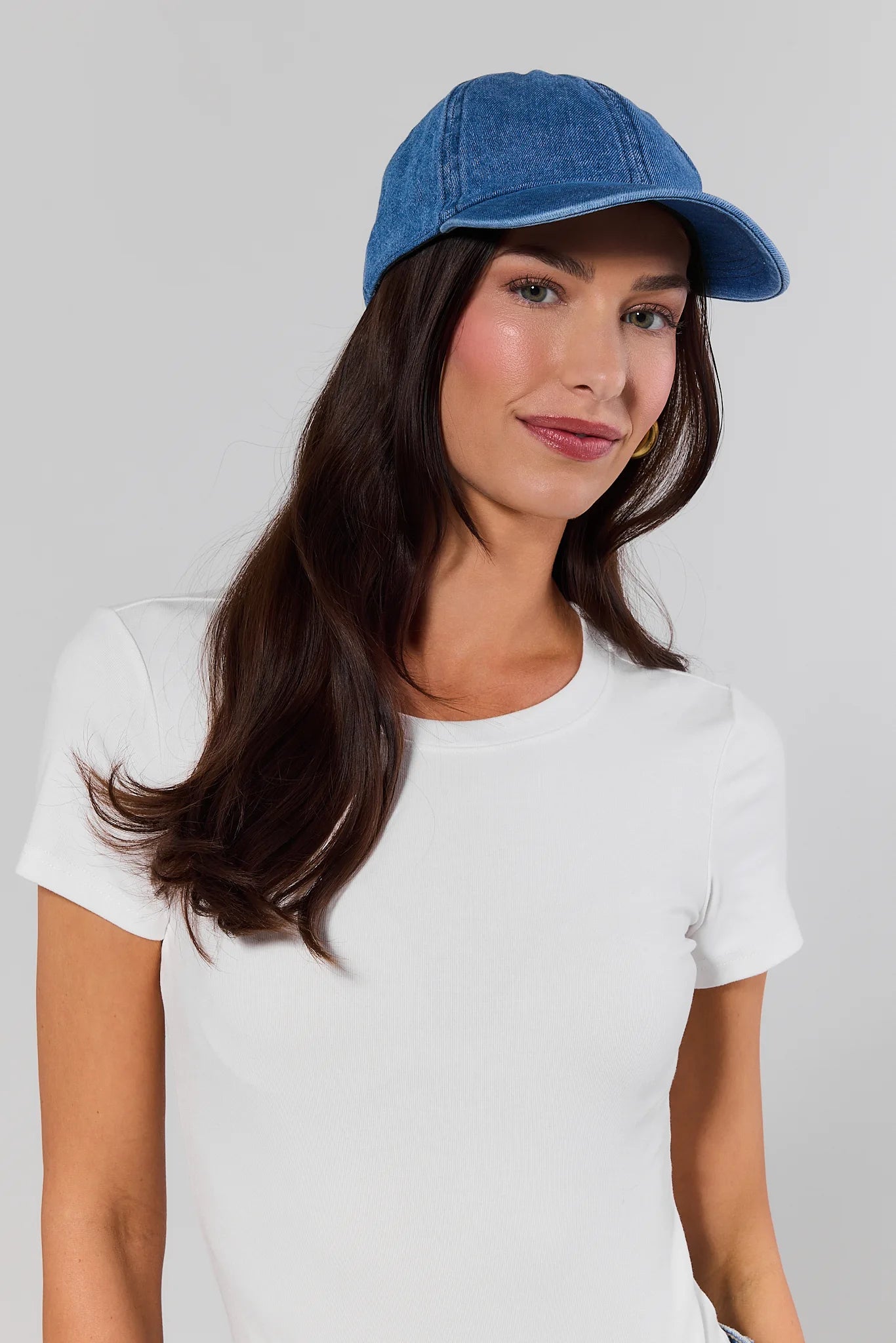 Woman wearing a blue cap and white t-shirt on a gray background
