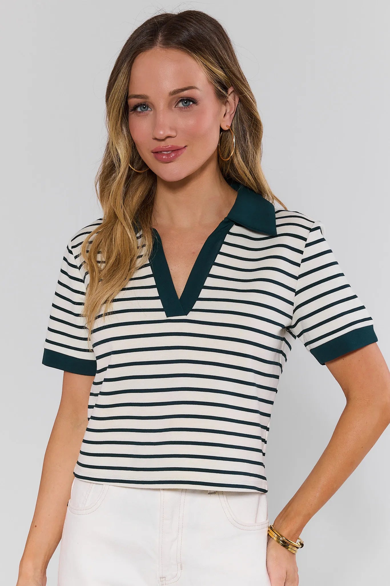 Woman wearing a striped shirt with green trim against a plain background