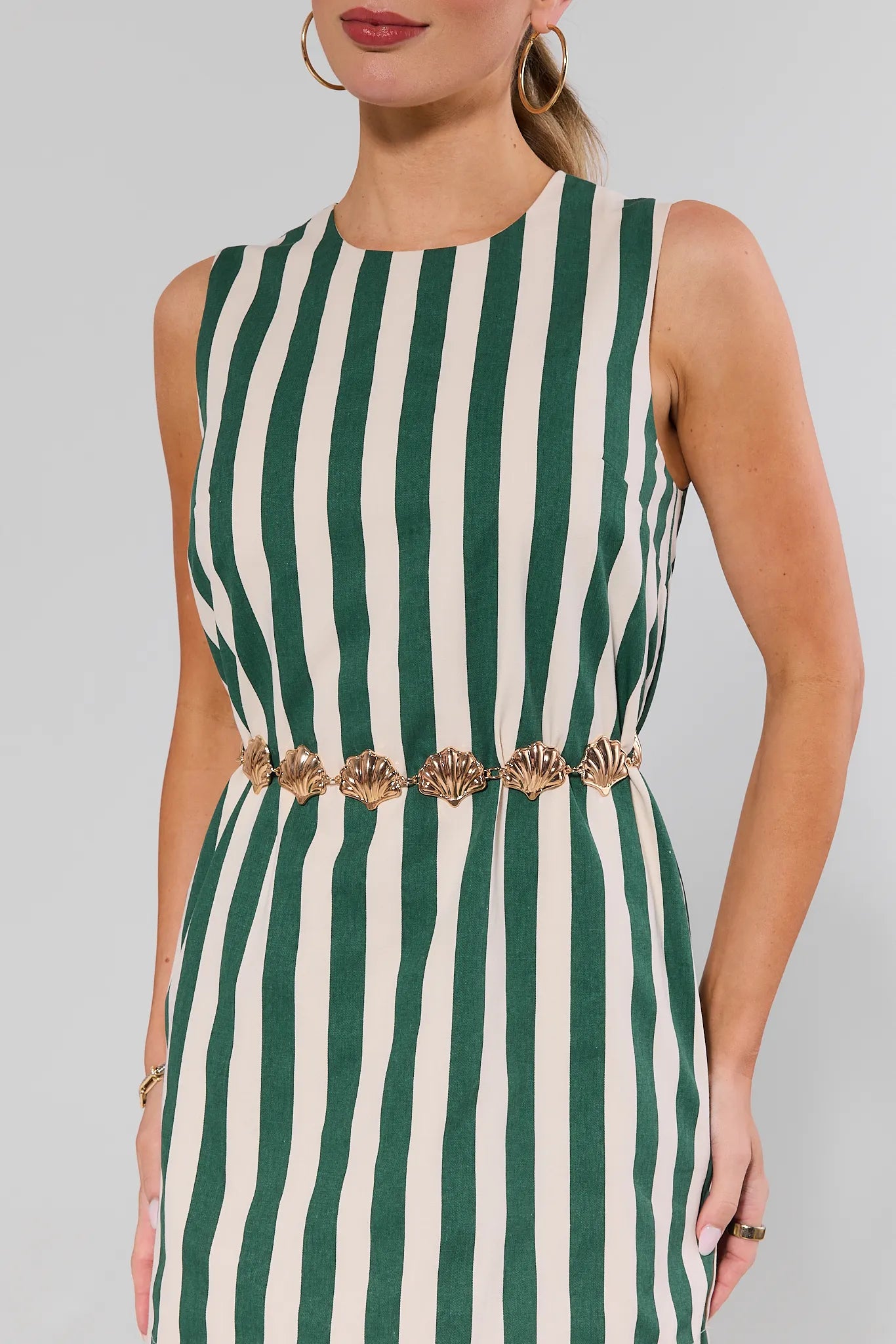 Green and white striped dress with a gold shell belt worn by a person on a gray background