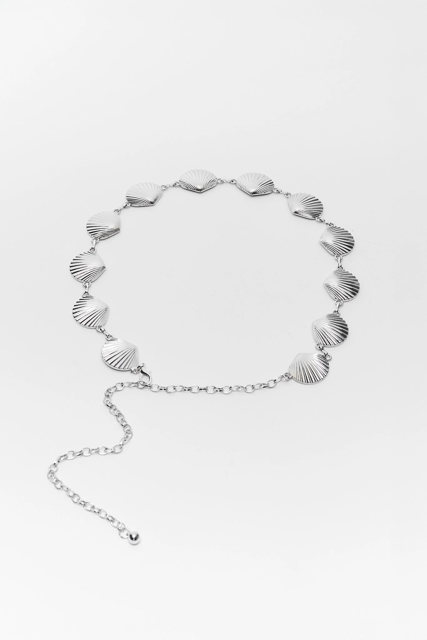 Silver chain belt with shell-like patterns on a white background