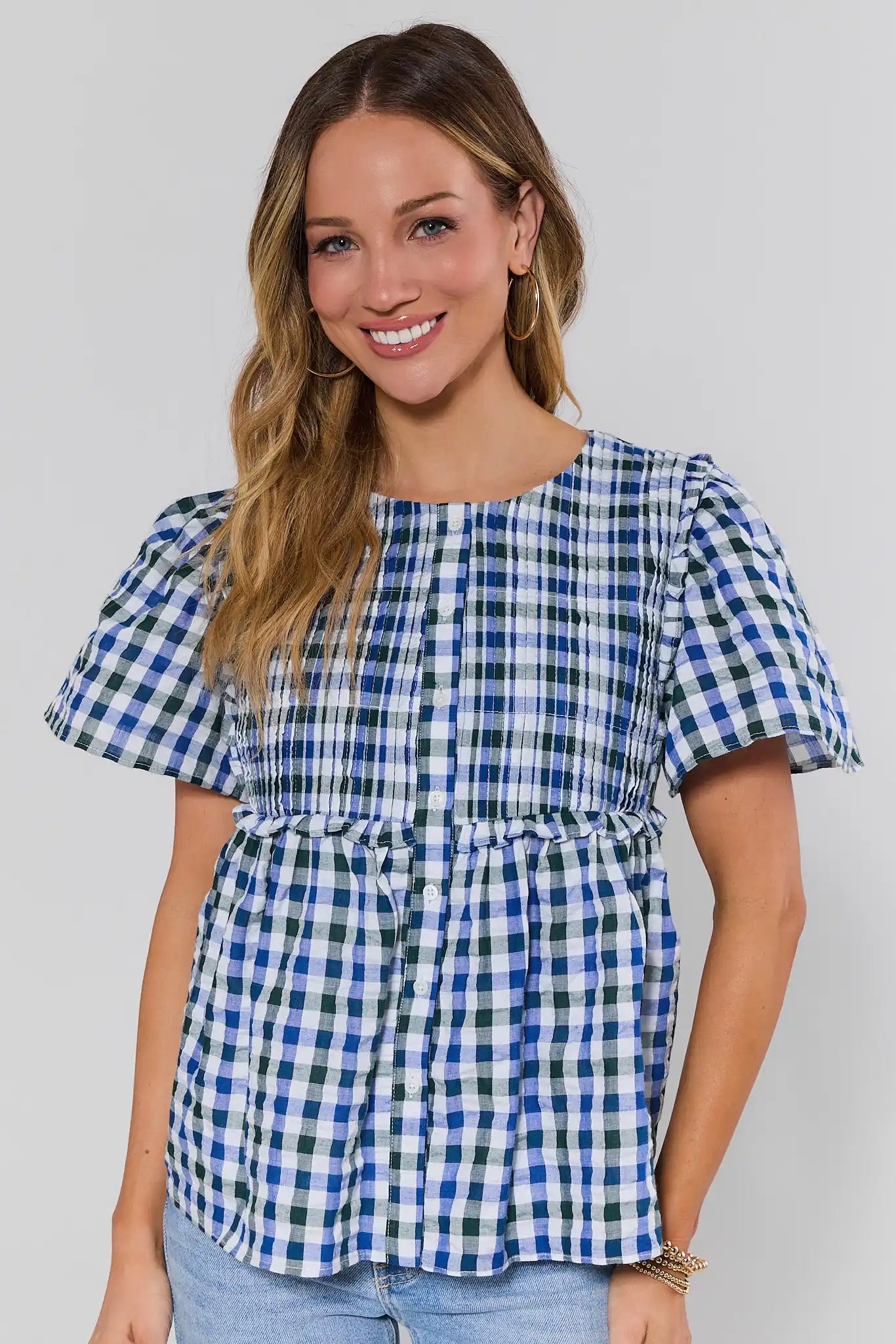 Woman wearing a blue and white checkered top against a plain background