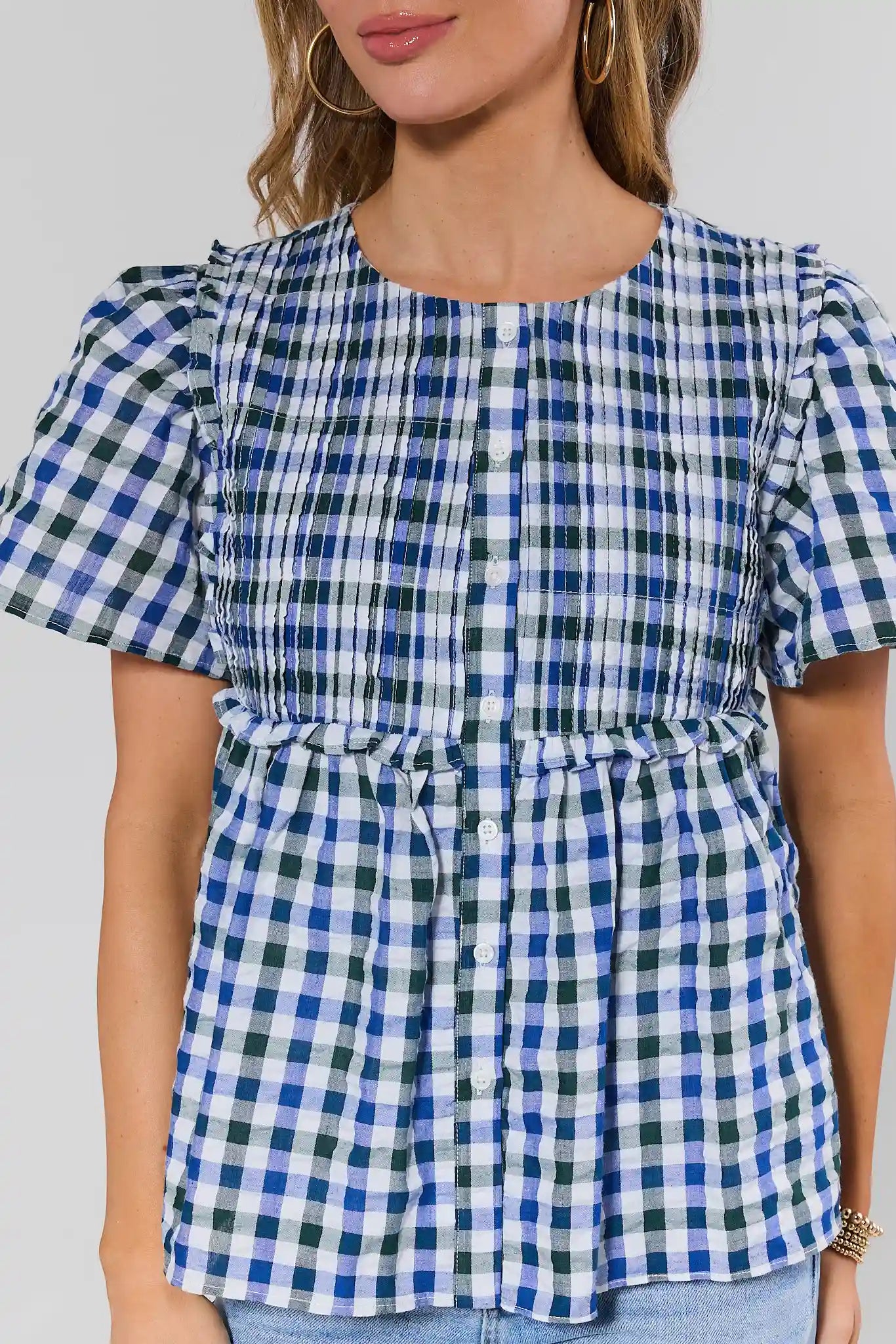 close up Woman wearing a blue and white checkered blouse against a plain background