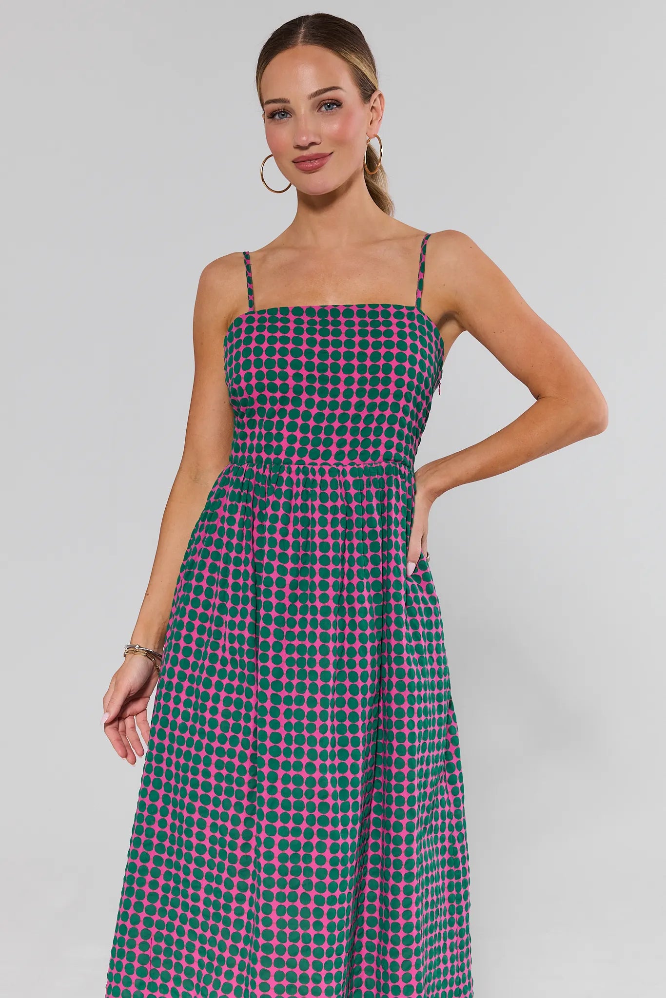 Woman wearing a green and pink checkered dress against a gray background