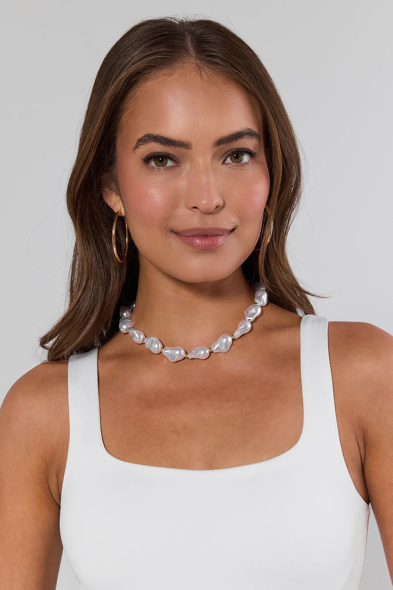 Woman wearing a pearl necklace against a plain background