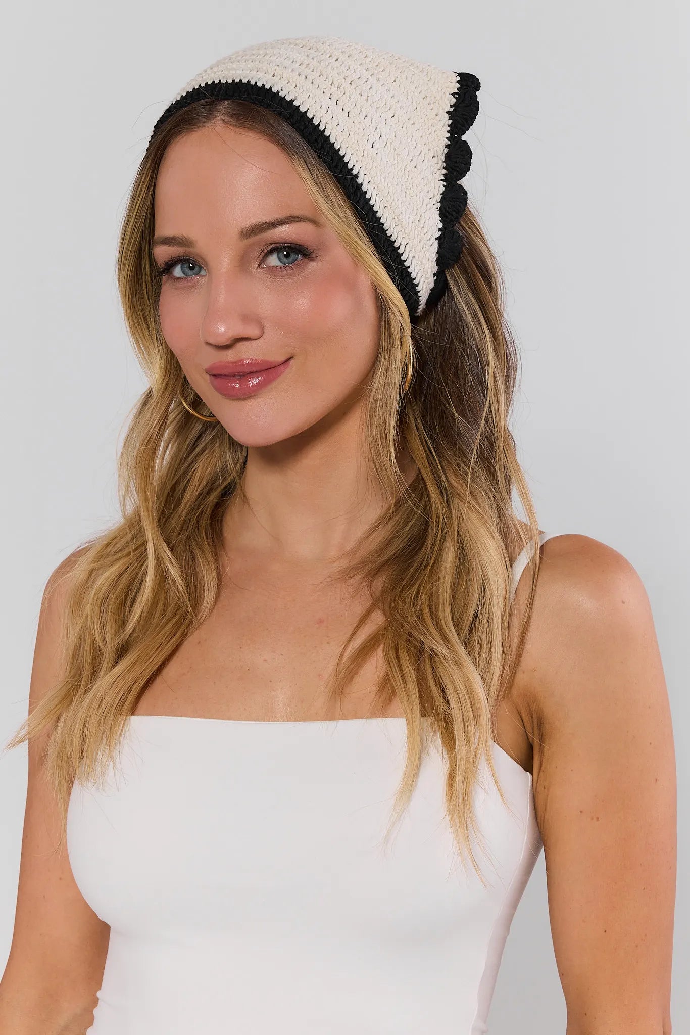Woman wearing a white and black knit headband against a plain background