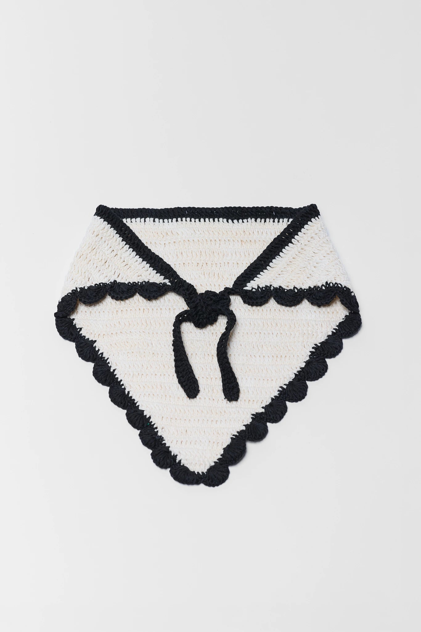 Black and white knitted baby blanket with a bow on a light gray background
