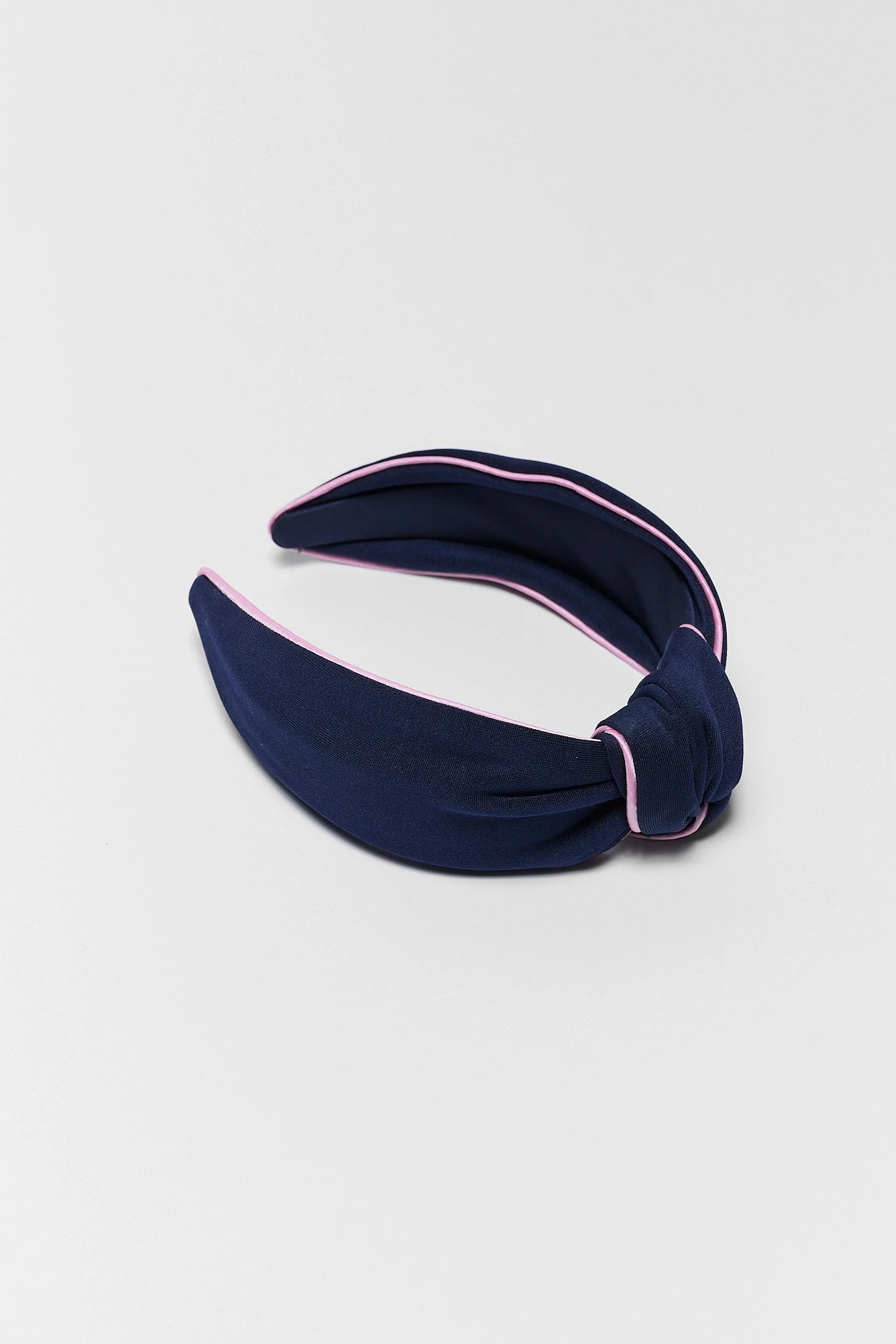 Navy blue headband with pink trim on a light gray background