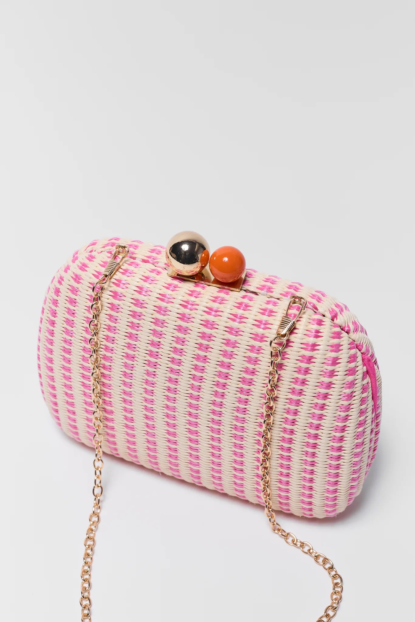 Pink and white striped clutch bag with decorative elements on a light gray background