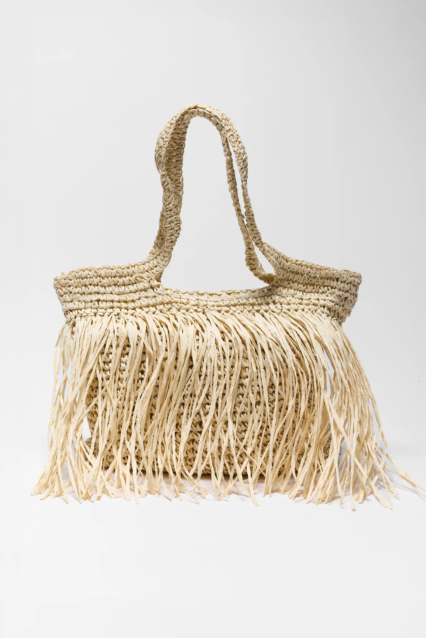 Woven handbag with fringe details on a white background