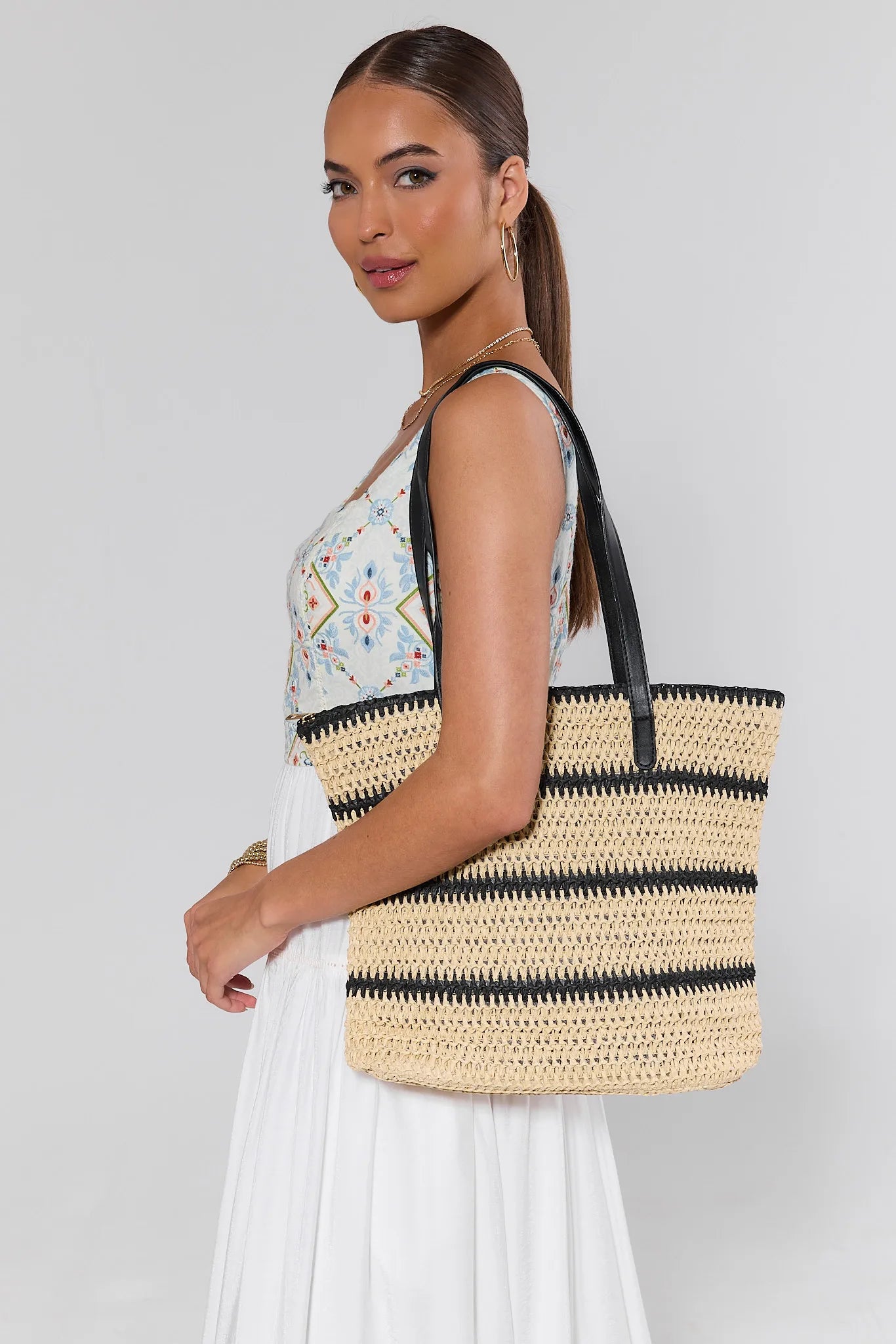 Woman holding a straw tote bag with a plain background