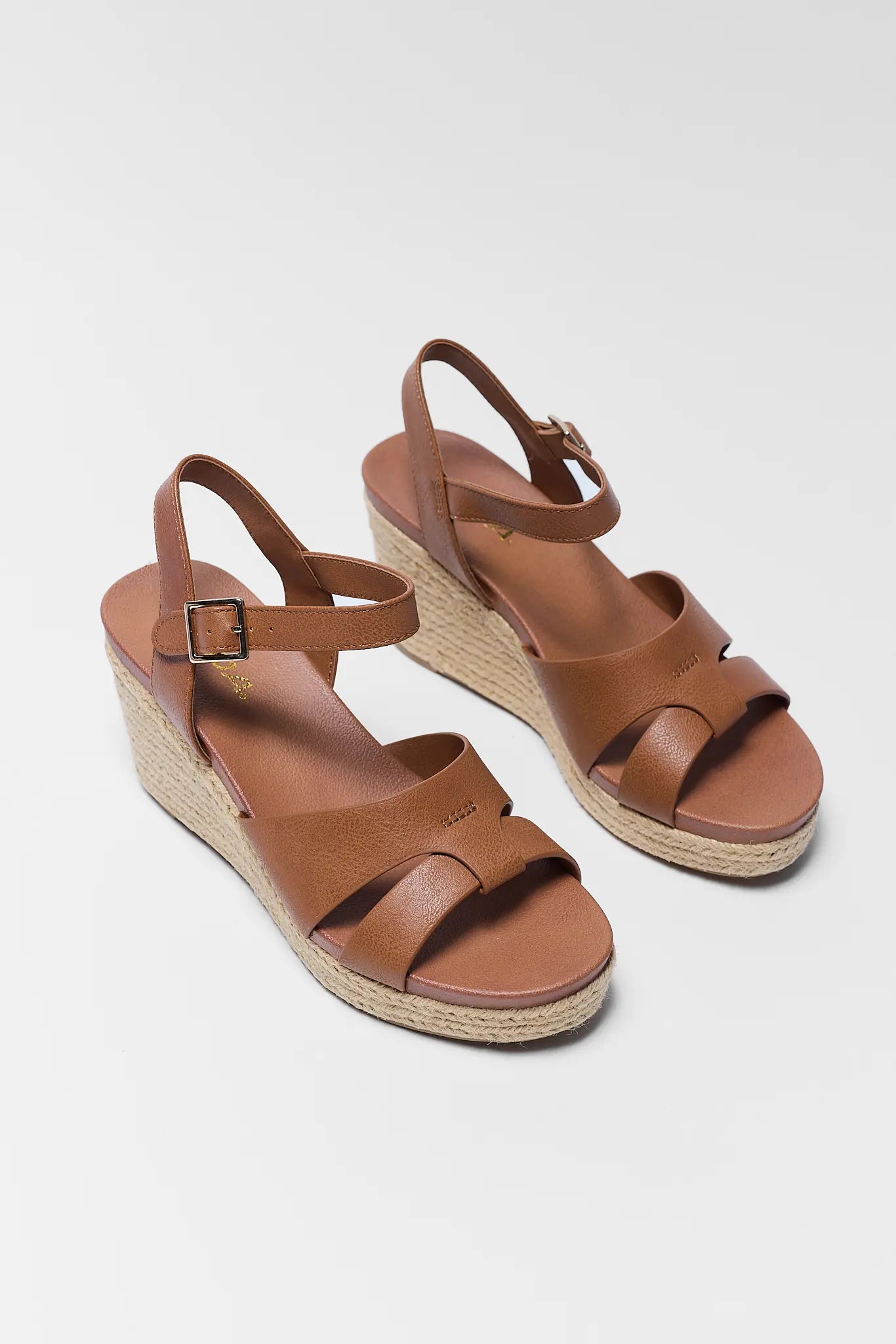 Pair of brown wedge sandals on a gray background