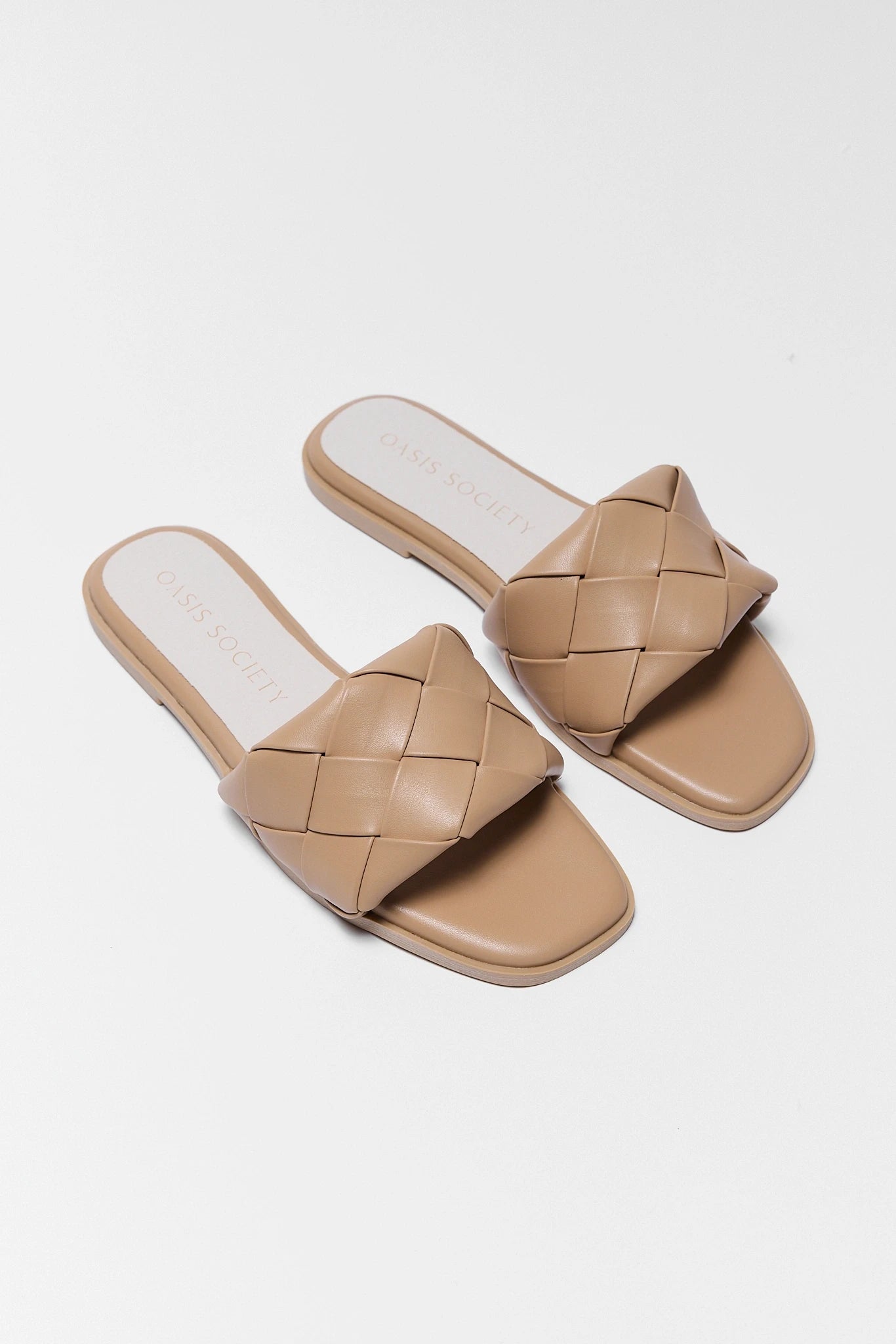 Pair of beige woven sandals on a white grey background