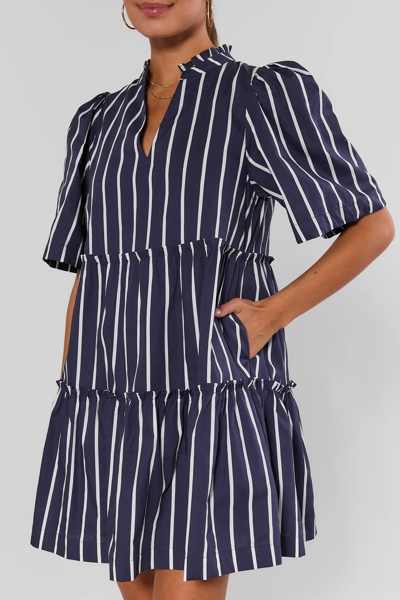 Woman wearing a navy and white striped dress against a plain background close
