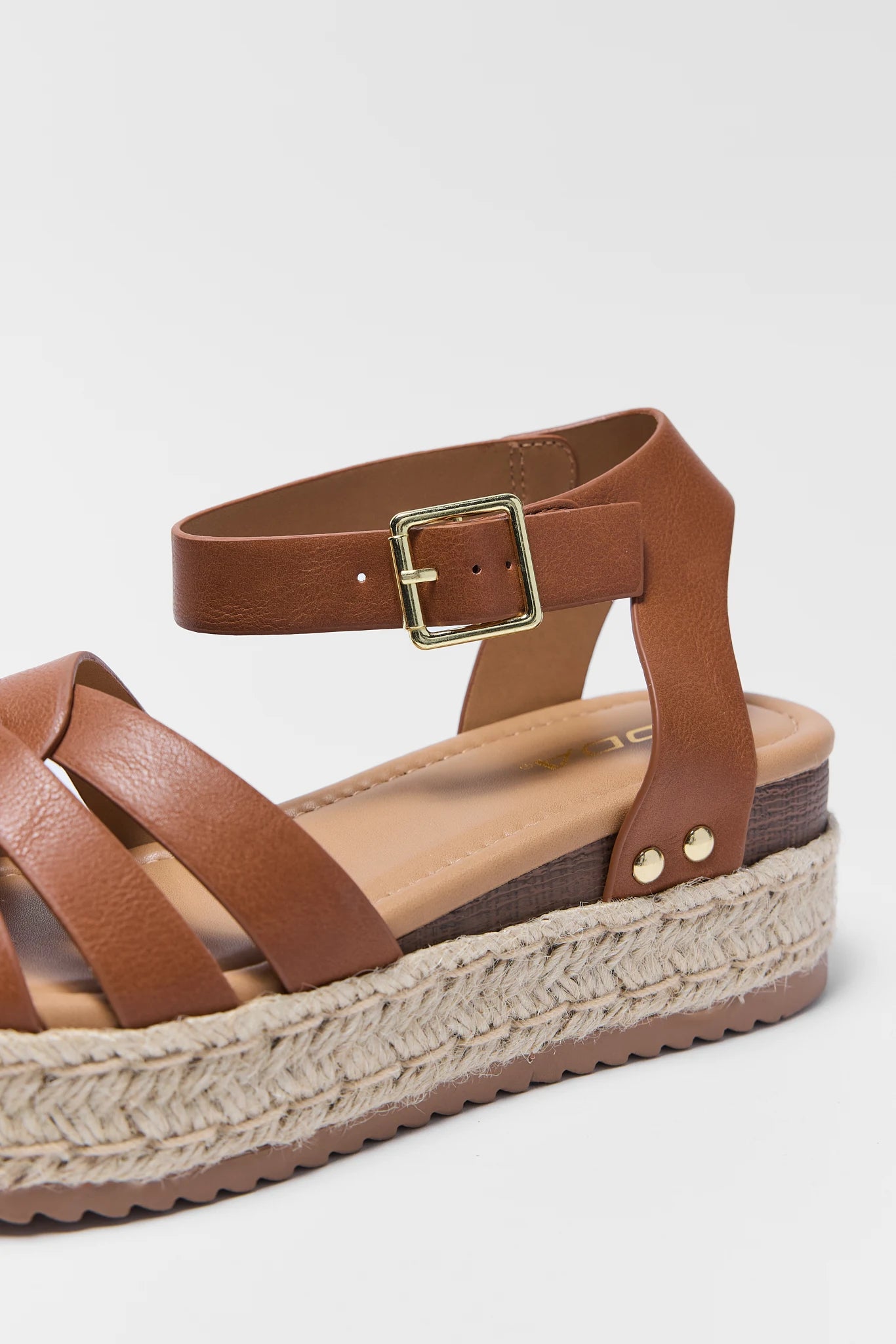 Brown sandal with woven sole on a light gray background close up