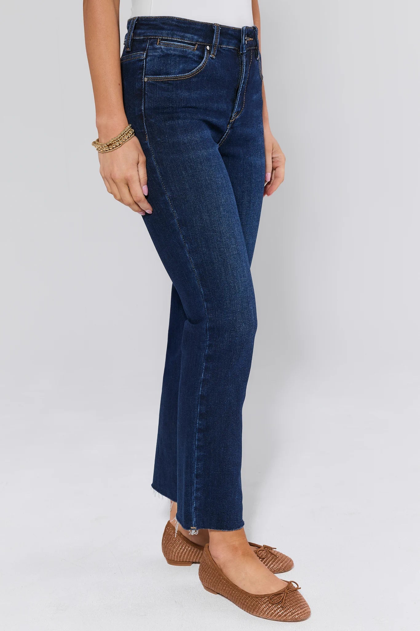 Person wearing blue jeans on a white background with brown ballet flats