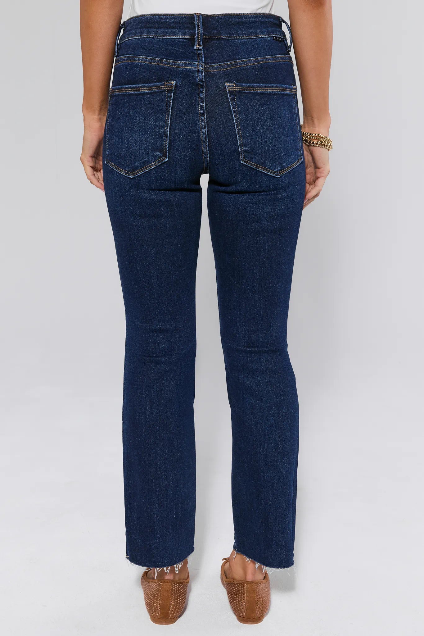 Person wearing dark blue jeans on a white background facing backwards