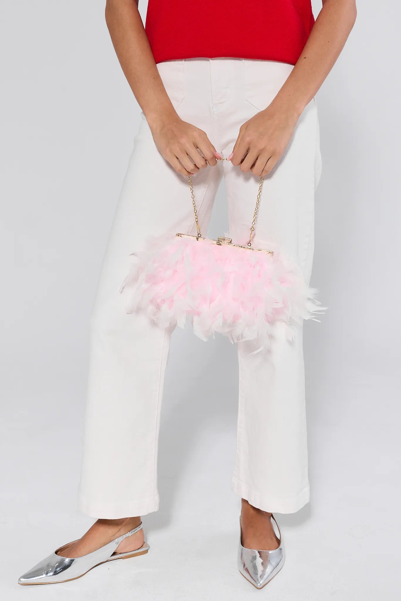 Person holding a pink feathered handbag against a white background