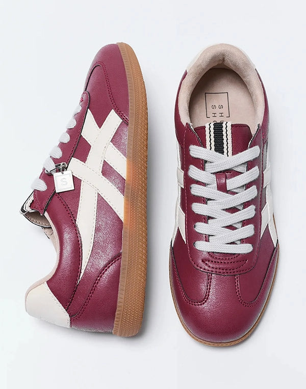 Pair of maroon sneakers with white accents on a light gray background