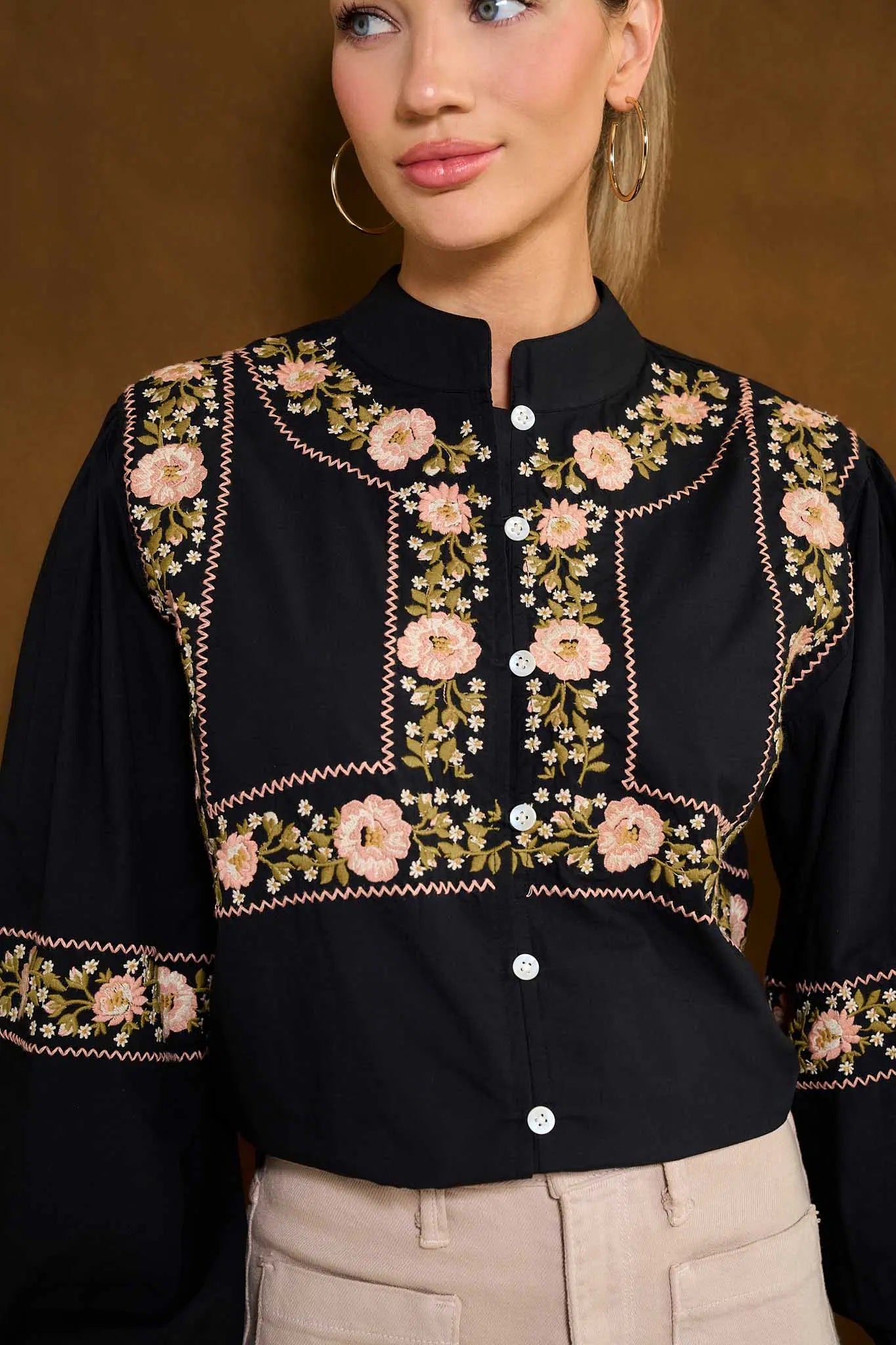 Black Selma Top with floral embroidery worn by a model against a brown background